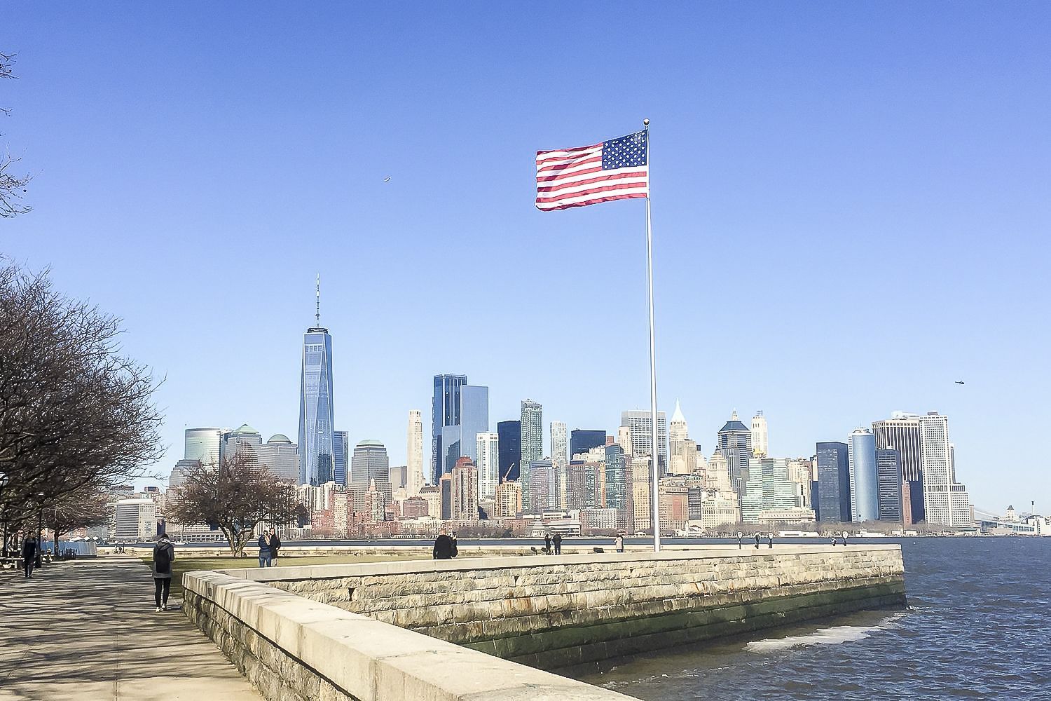 American flag flies over the New York City skyline, with the Freedom Tower visible.