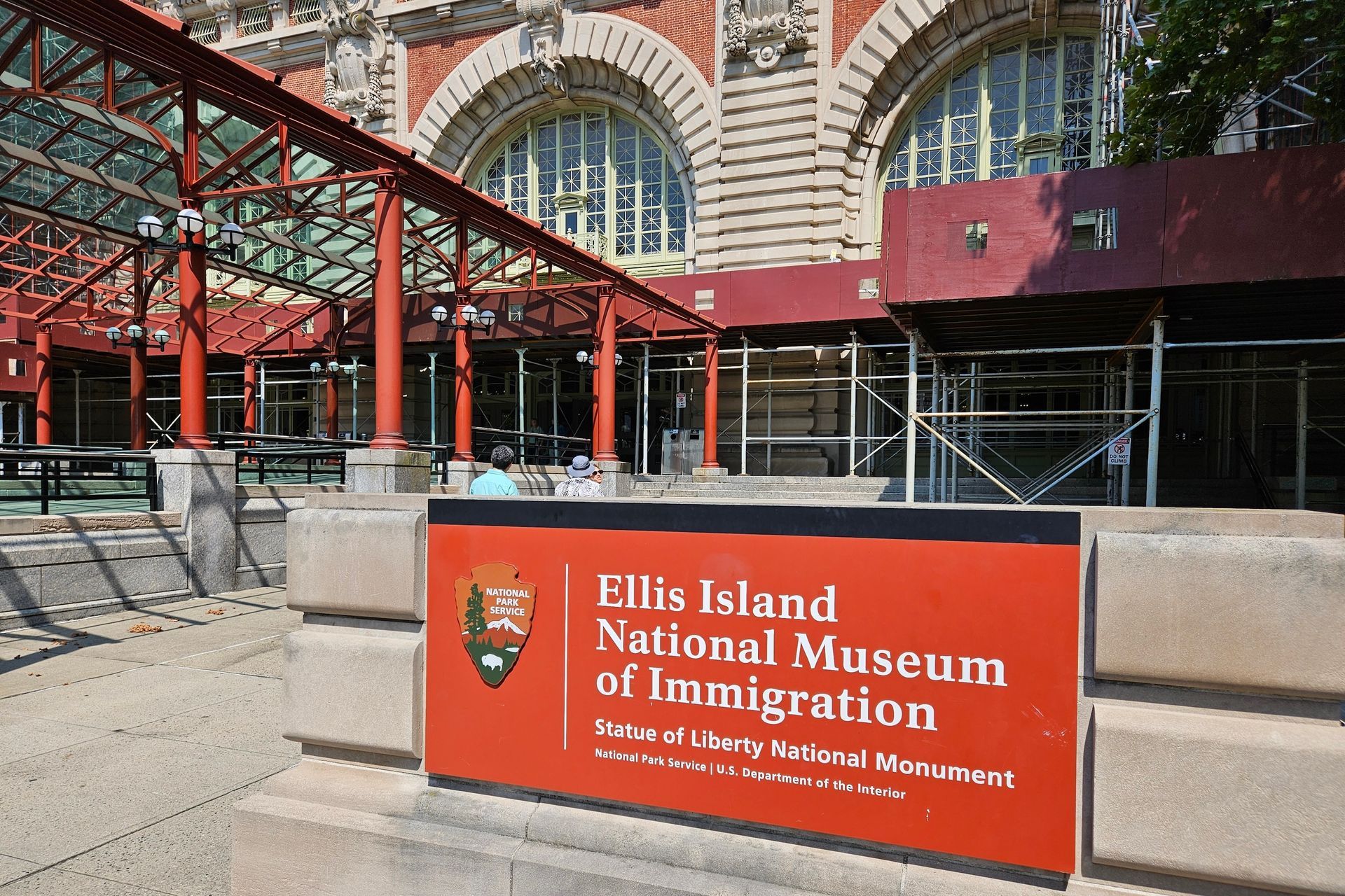 Ellis Island National Museum of Immigration building exterior. Red sign, brick structure, and brown awning.