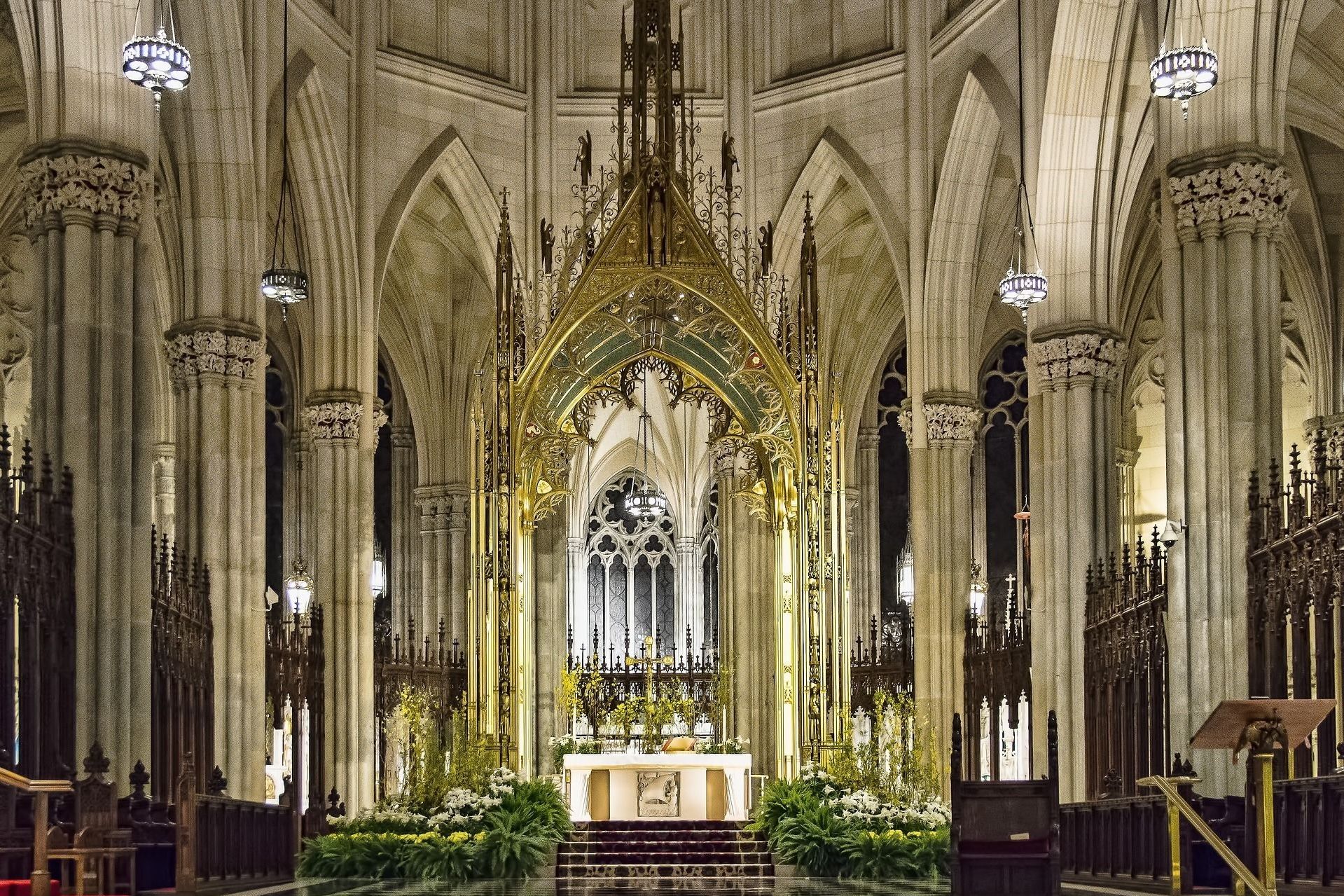 Interior of St. Patrick's Cathedral in NYC, with ornate altar and columns, soft lighting.