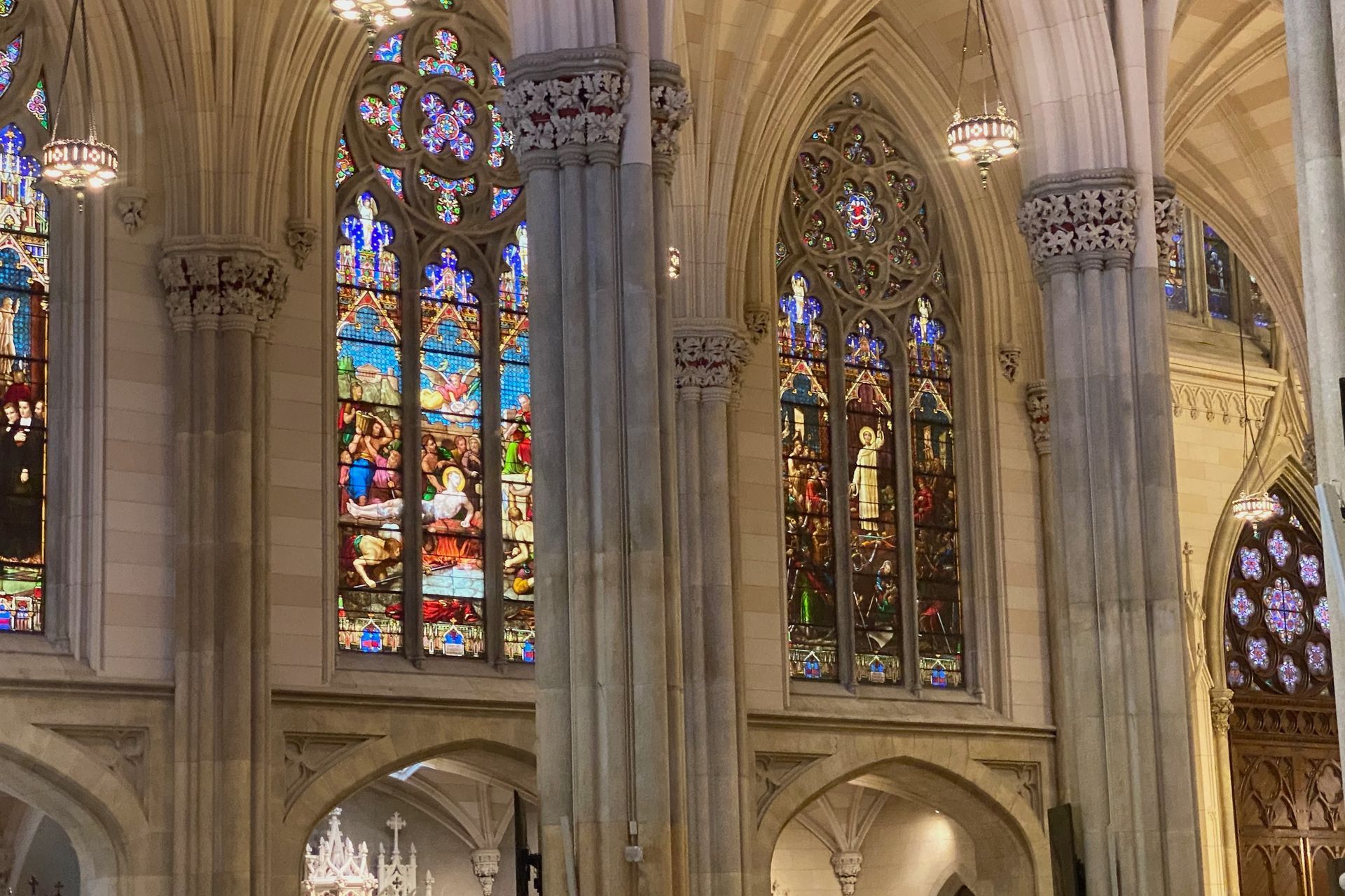 Stained glass windows inside a cathedral, with light streaming through the colorful panes.