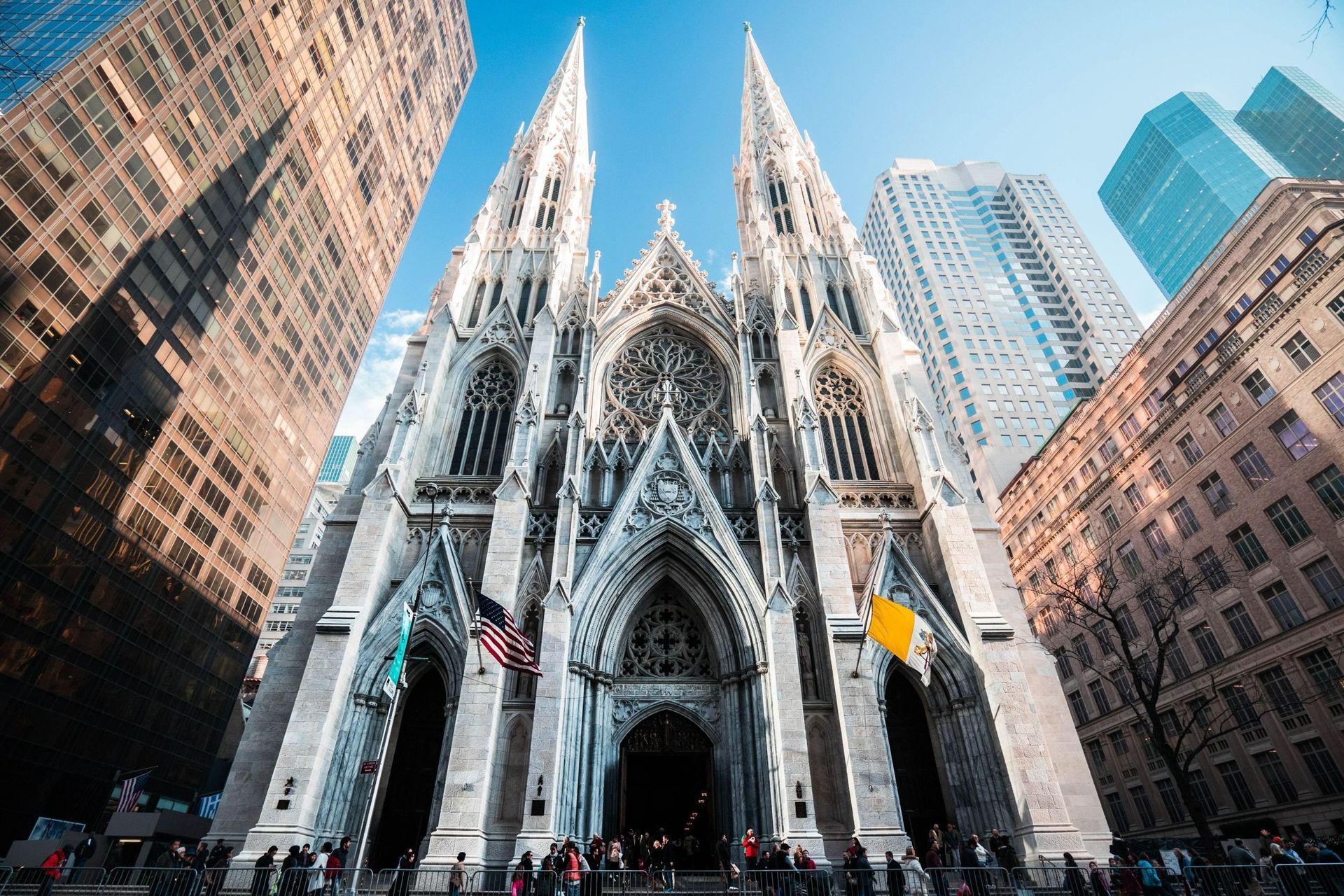 St. Patrick's Cathedral in New York City framed by skyscrapers on a sunny day.