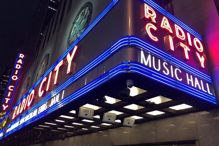 Radio City Music Hall sign lit up in red and blue neon at night.