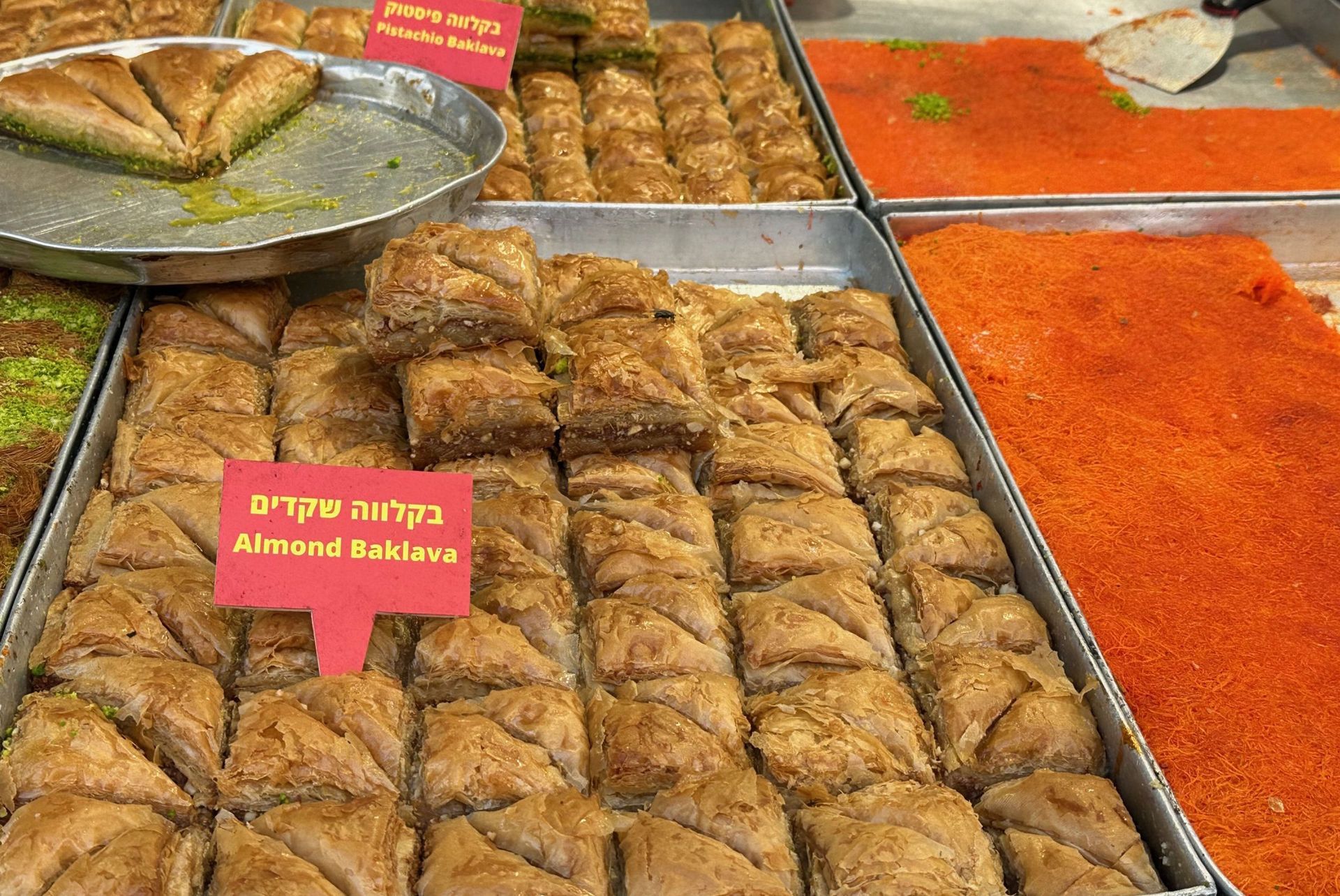 Display of various baklava pastries with red labels in a shop.