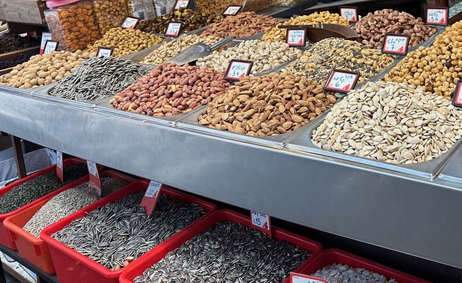 A variety of nuts and seeds displayed for sale in bins at a market.