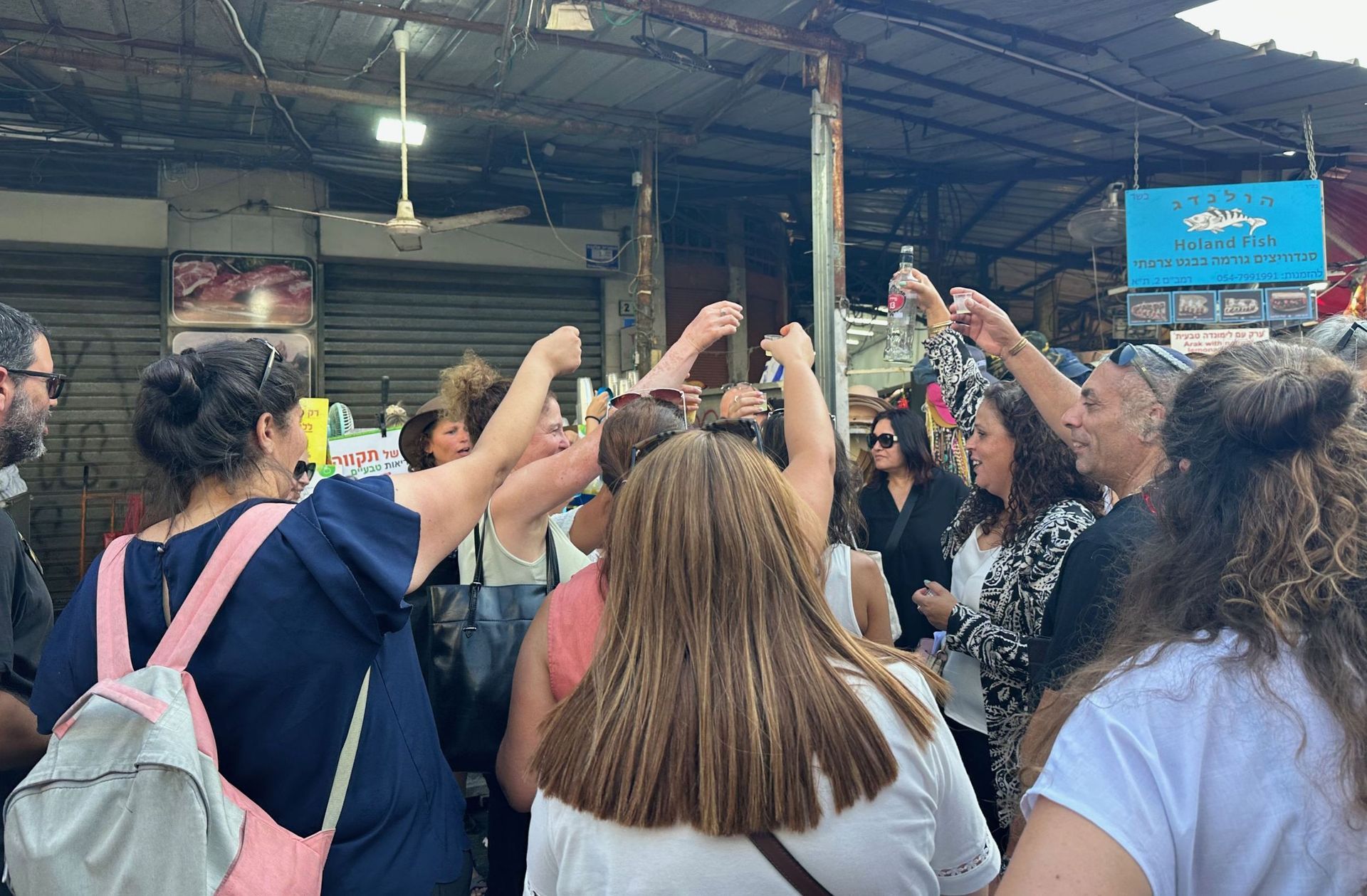 People in a market setting with arms raised, celebrating.