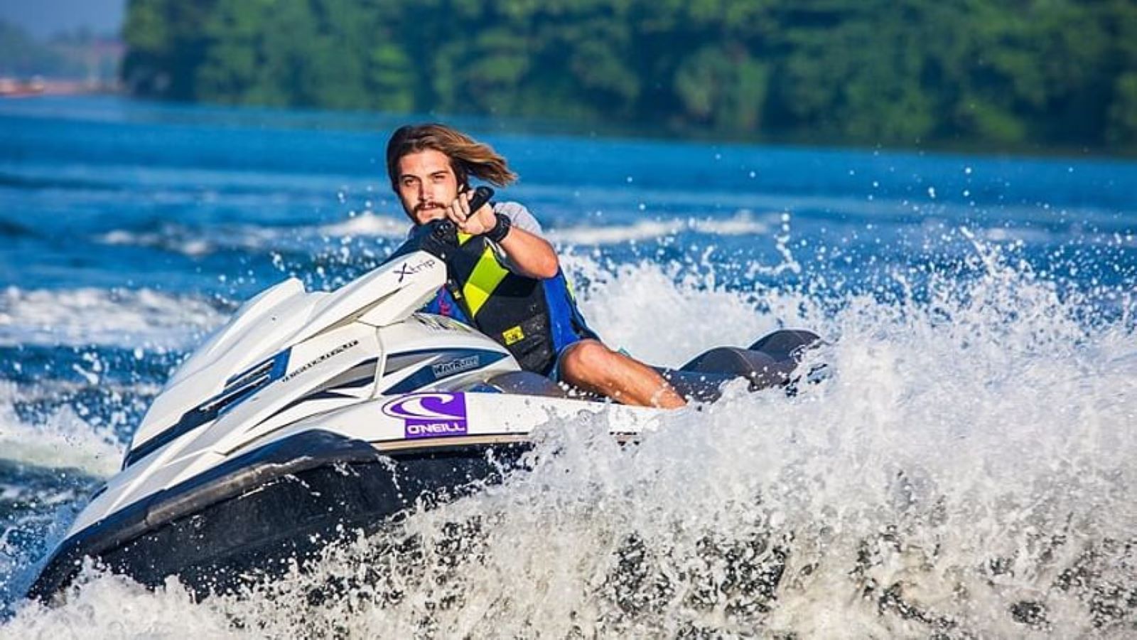 Man on a jet ski, leaning, making a turn, surrounded by splashing water. Sunny day on a lake.