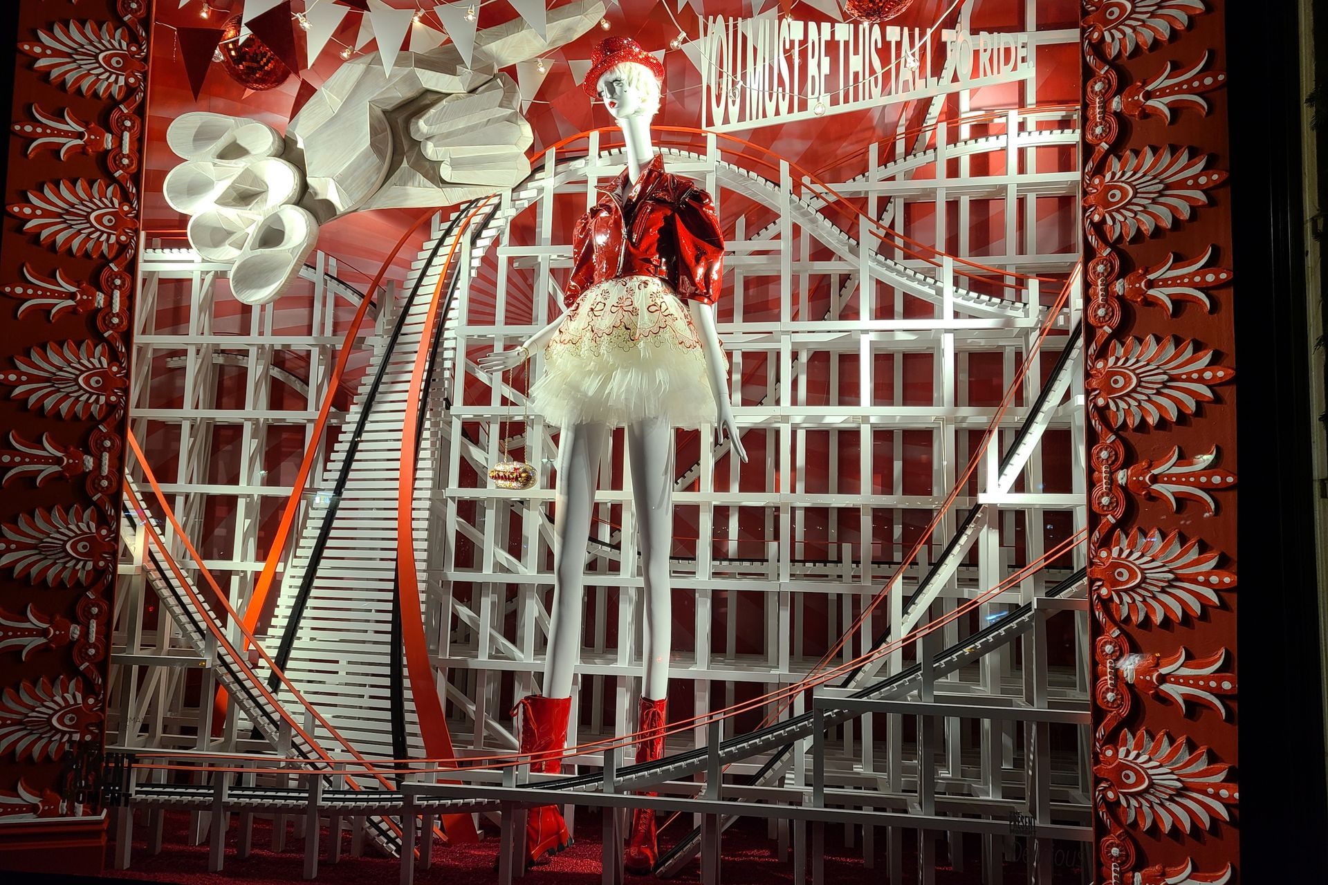 Window display with a mannequin in red attire, set in a white and red geometric structure.