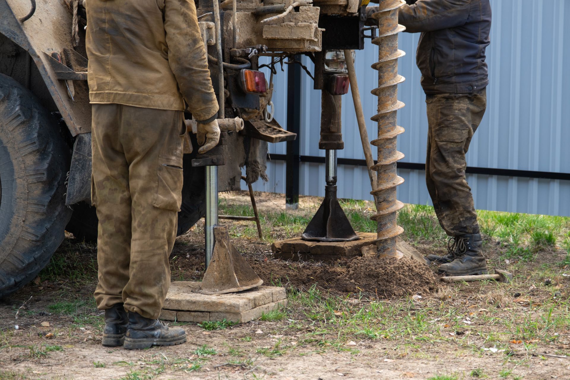 Team of workers with drilling rig on car are drilling artesian well for water in ground.
