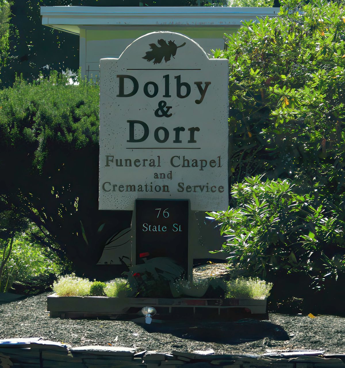 Sign for Dolby & Dorr Funeral Chapel and Cremation Service. Beige sign with black text, 76 State St address.