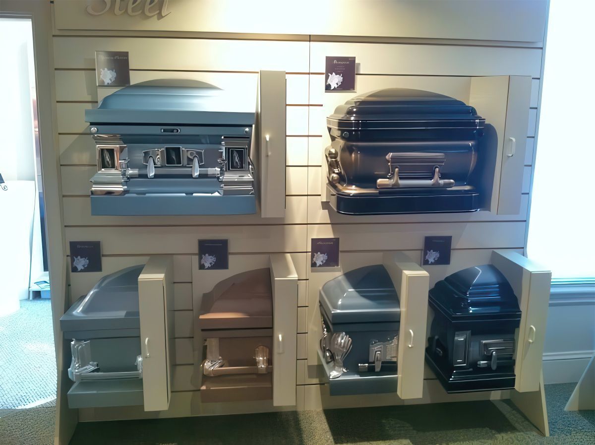 Display of various colored caskets on a wooden shelf in a showroom.