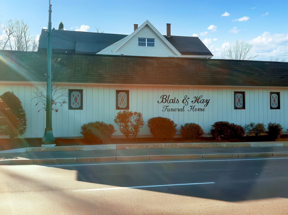 Blair E. Wertz Funeral Home, a white building with brown roof and windows. A street and blue sky are in view.
