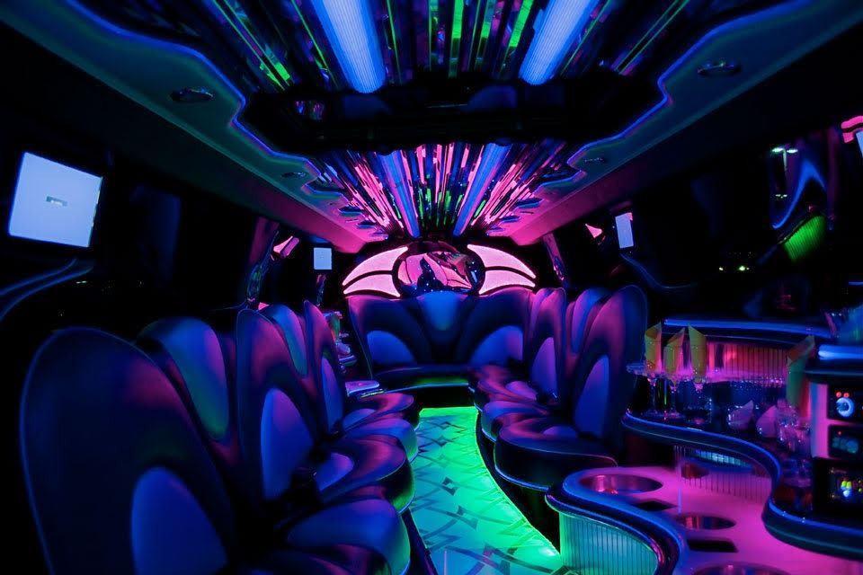 Neon-lit lounge interior with plush seats, glowing floor, and colorful ceiling lights in blue, purple, and green