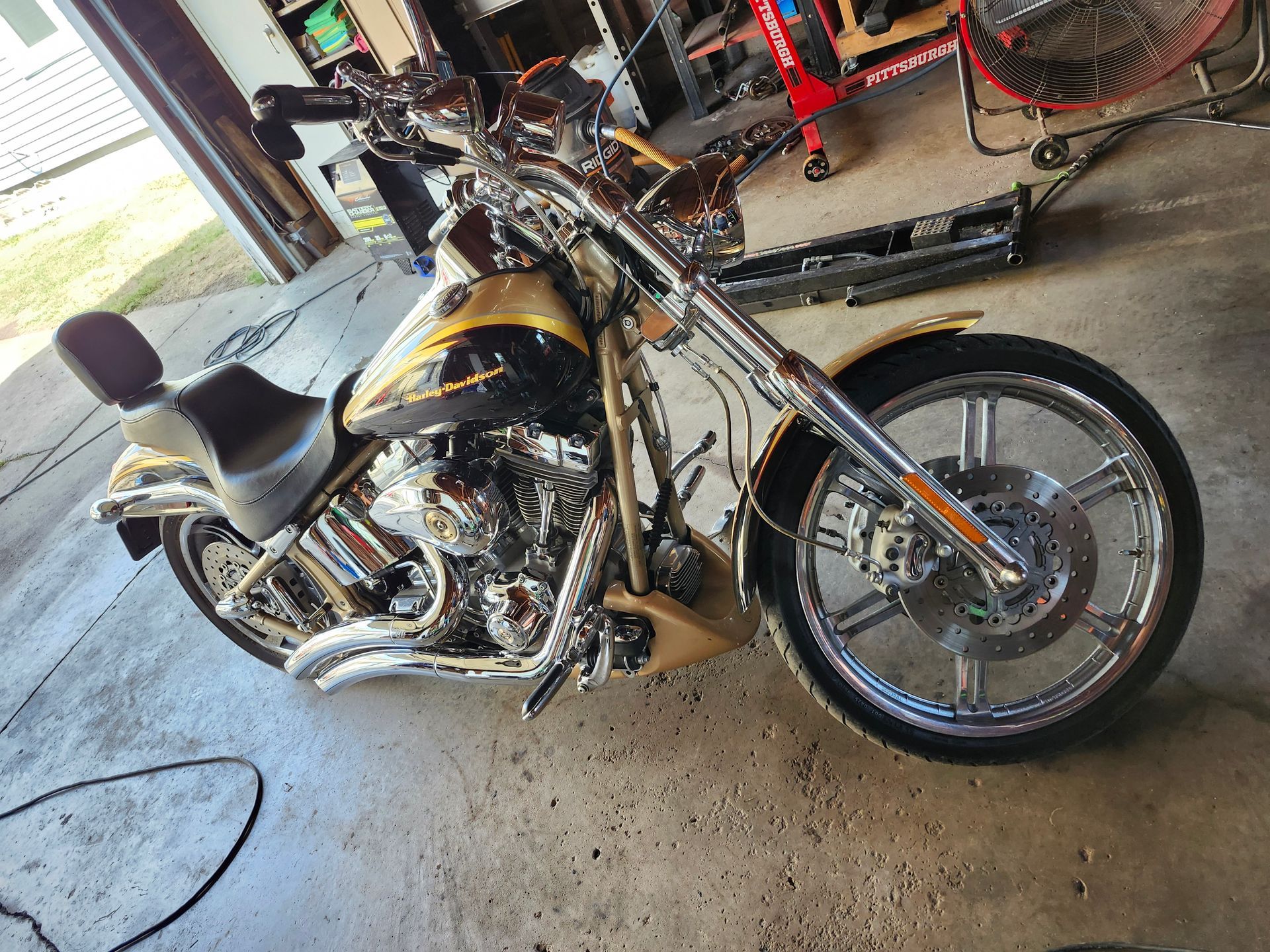 A motorcycle is parked in a garage next to a fan.