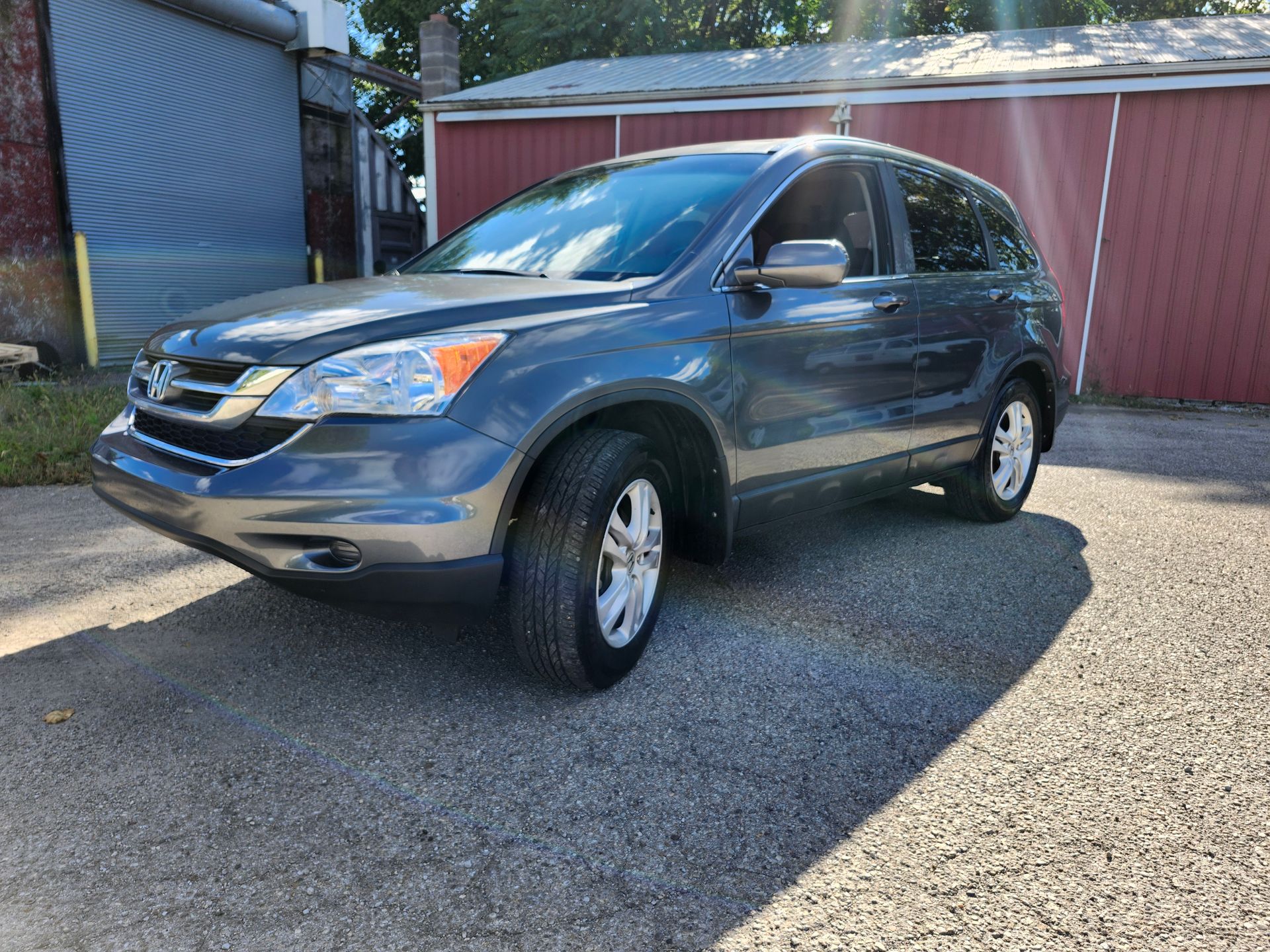A blue honda cr v is parked in front of a red garage door.