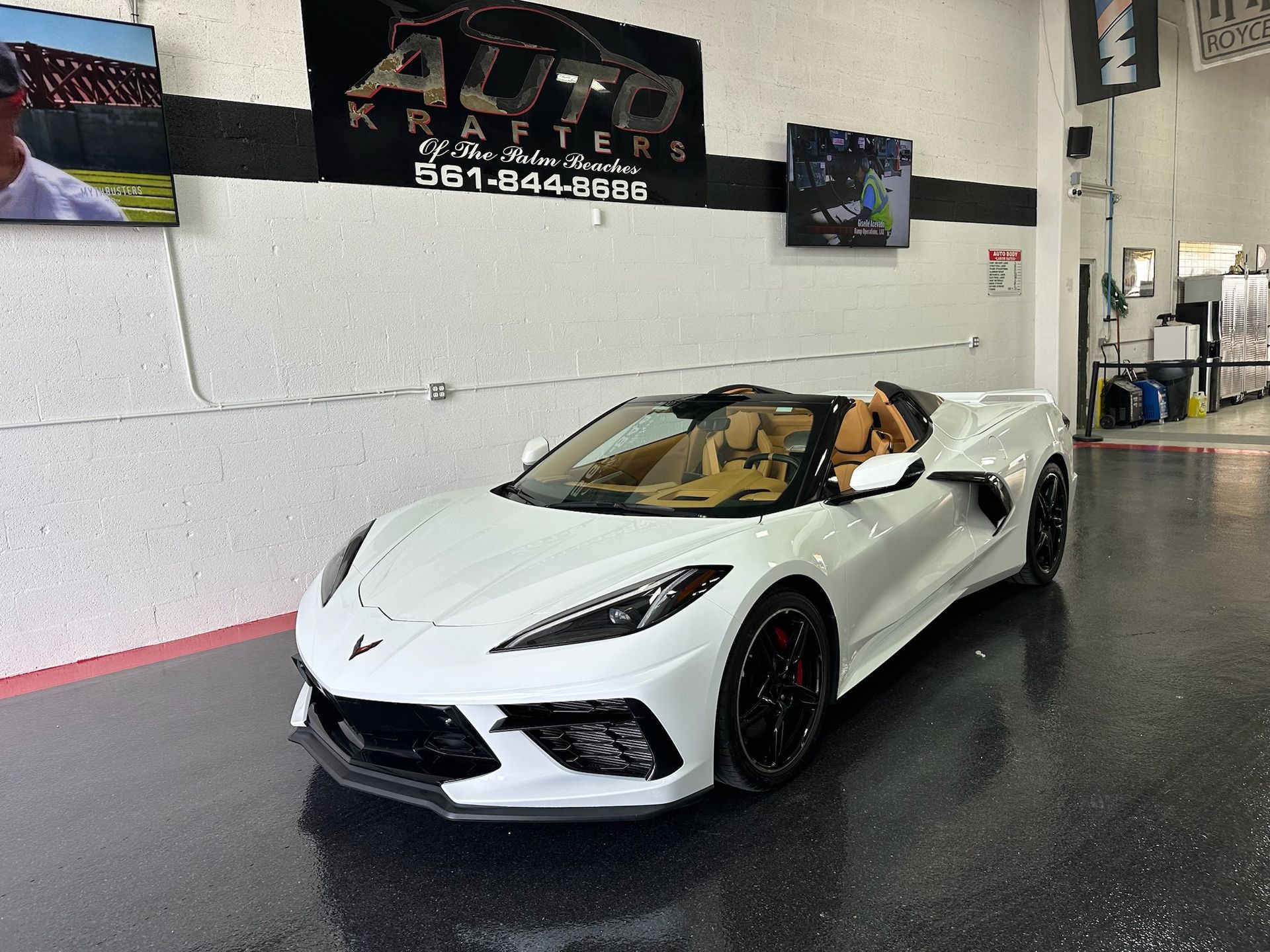 White Corvette convertible with tan interior in a shop.