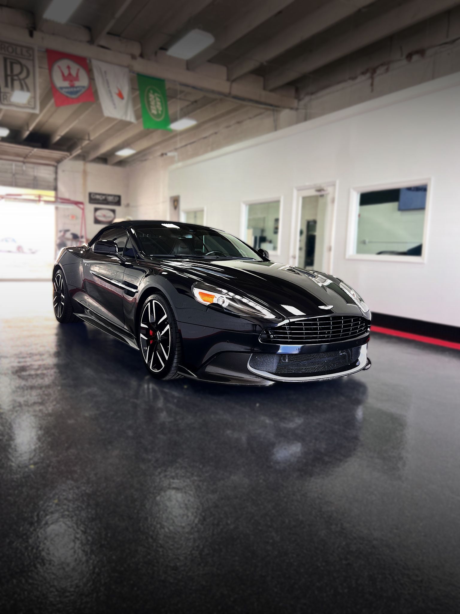 Black Aston Martin convertible in a showroom.