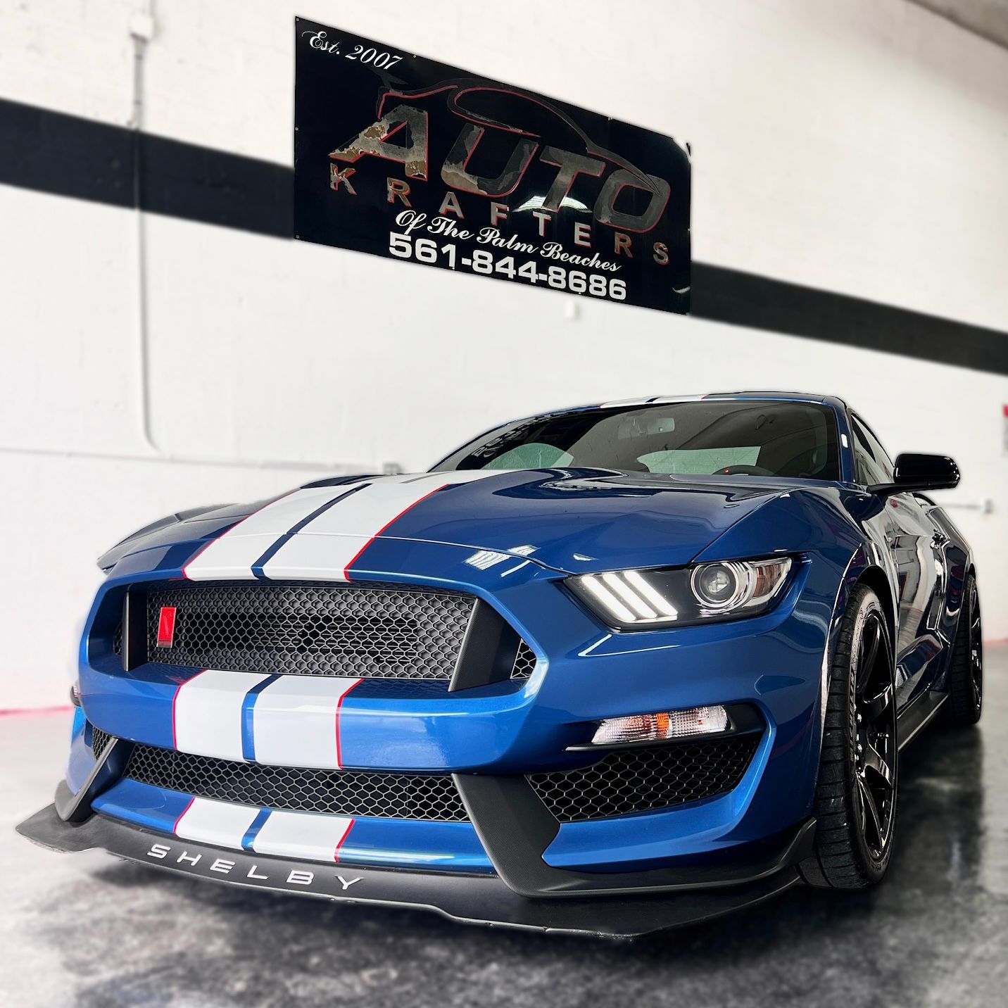 Blue Shelby Mustang with white stripes parked in front of 