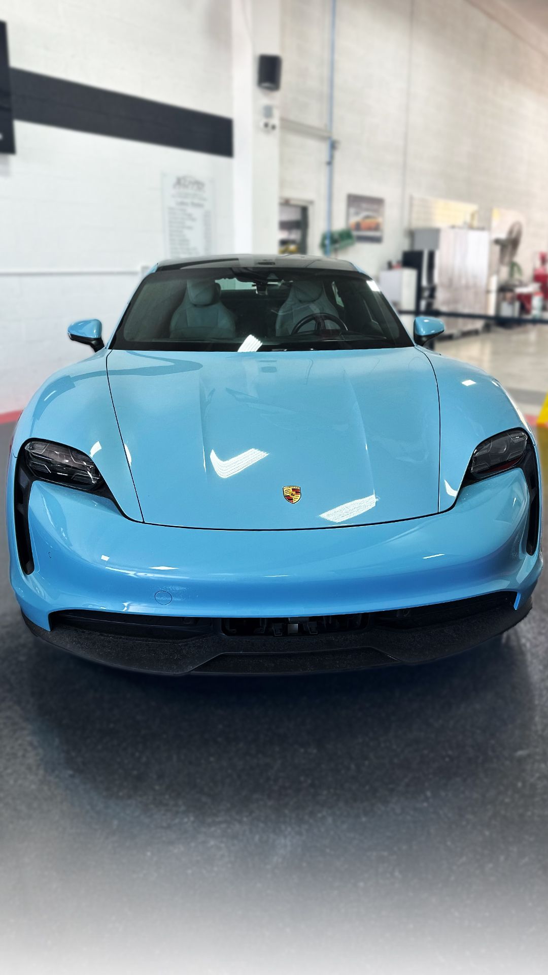 Light blue Porsche Taycan electric car in an indoor setting.