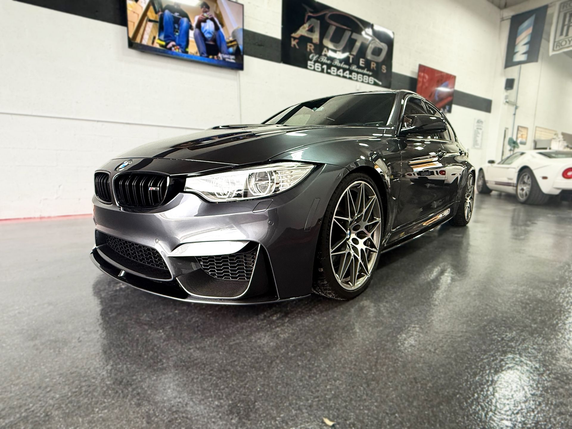 Dark gray BMW M4 coupe in a car shop.