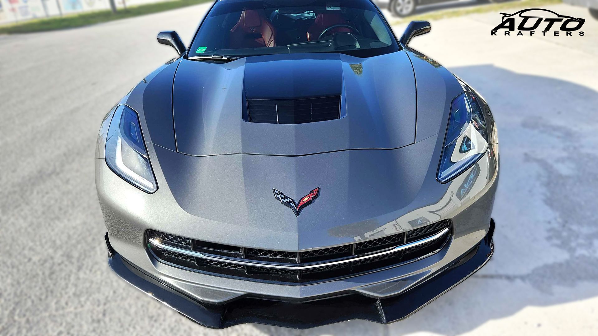 Gray Chevrolet Corvette sports car on road, front view.