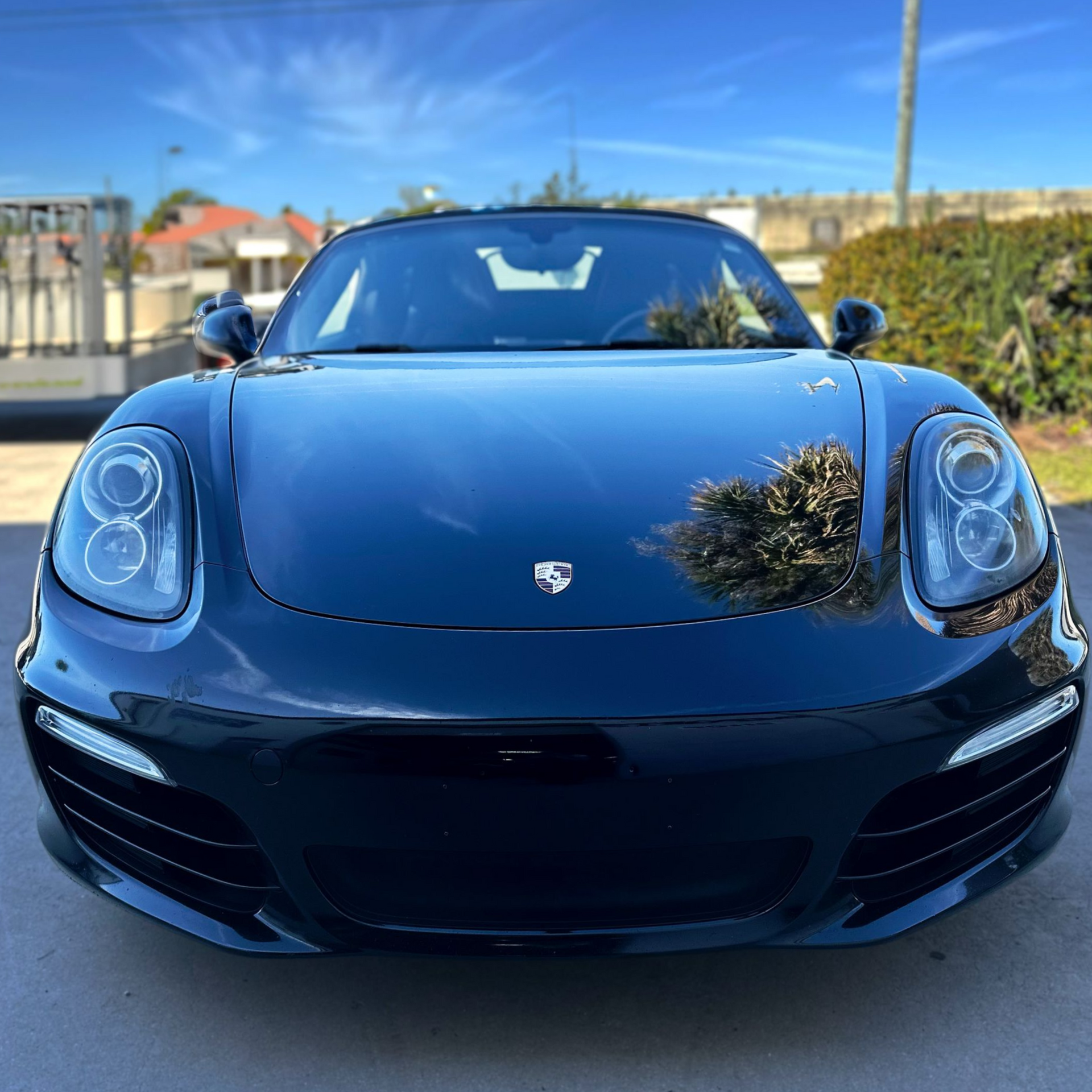 Black Porsche Boxster convertible, parked outside on a sunny day.