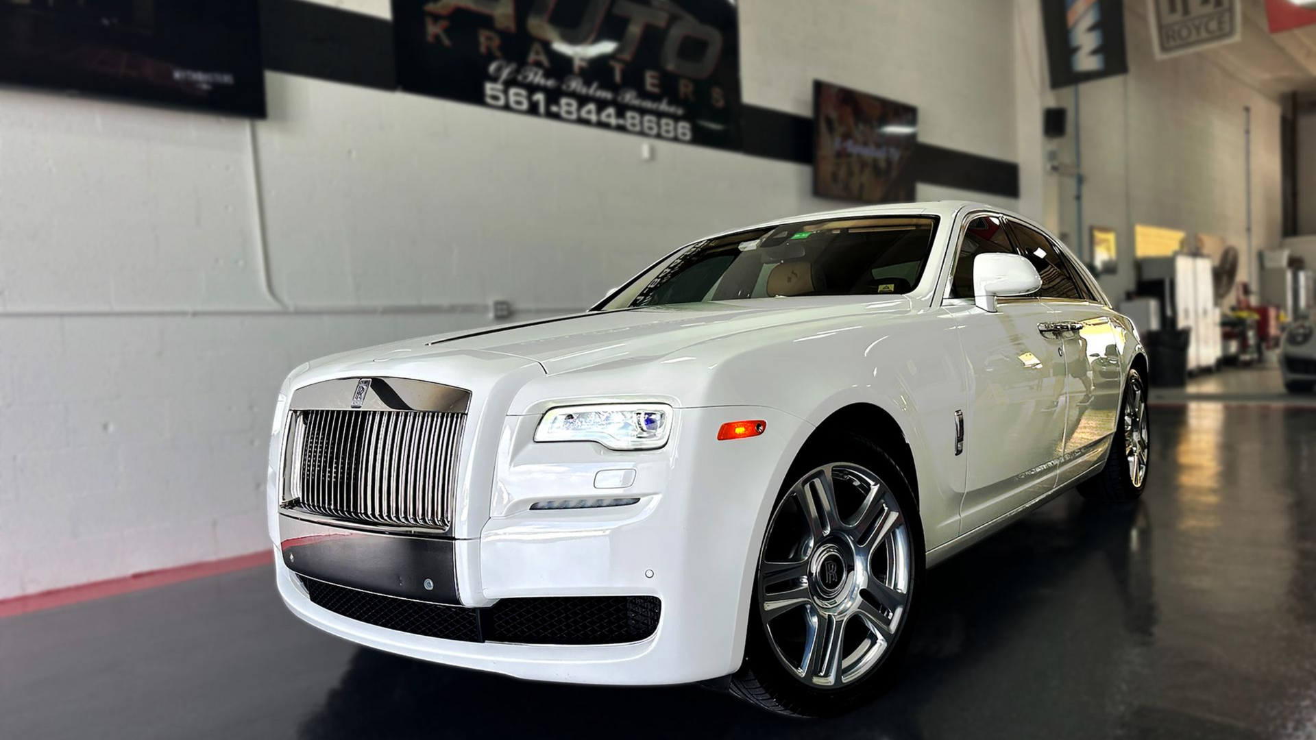 White Rolls Royce sedan parked inside a showroom.
