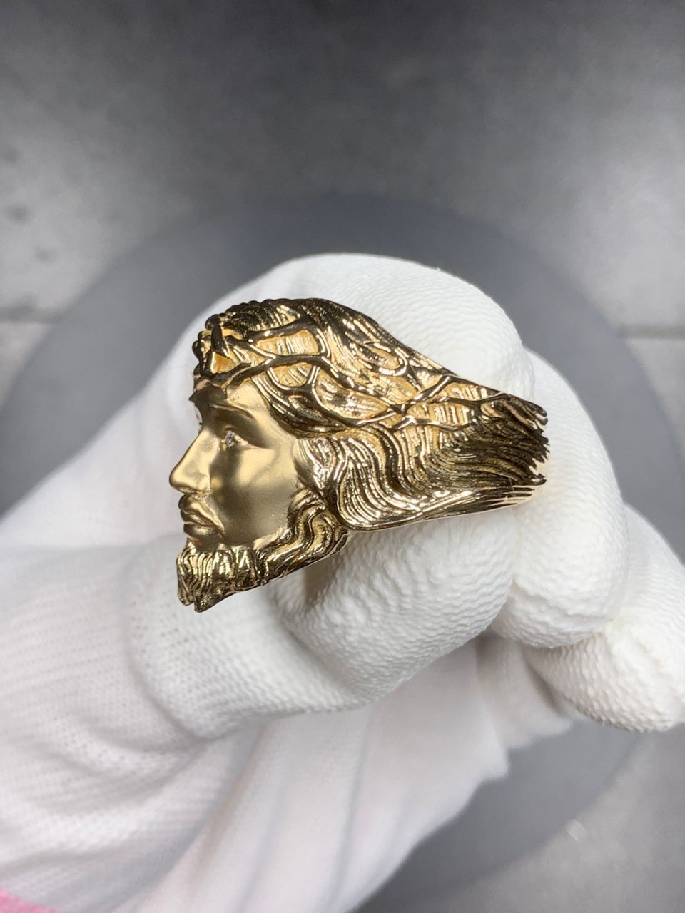 A person is holding a gold ring with jesus ' face on it