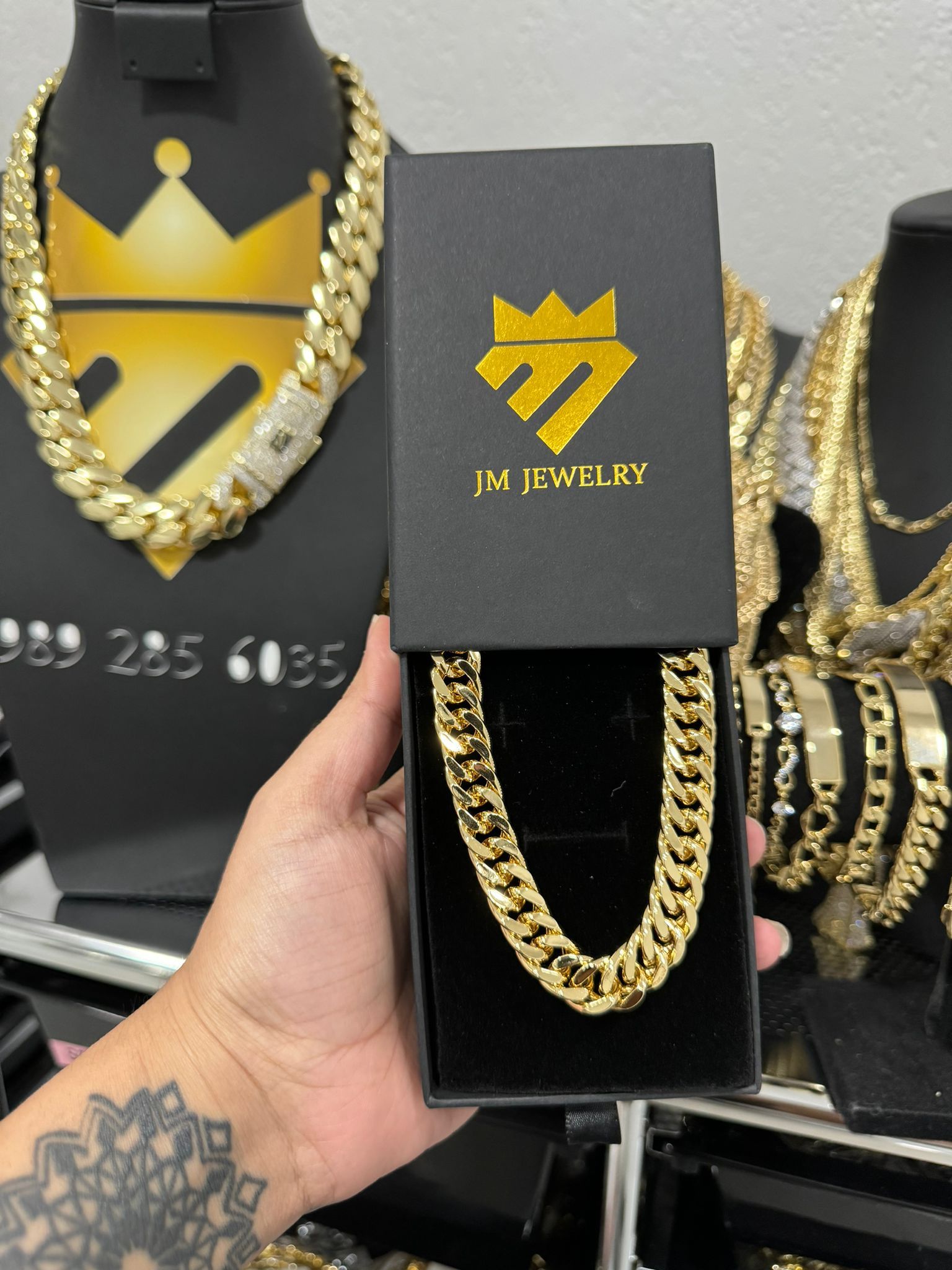 A person is holding a gold chain in a box