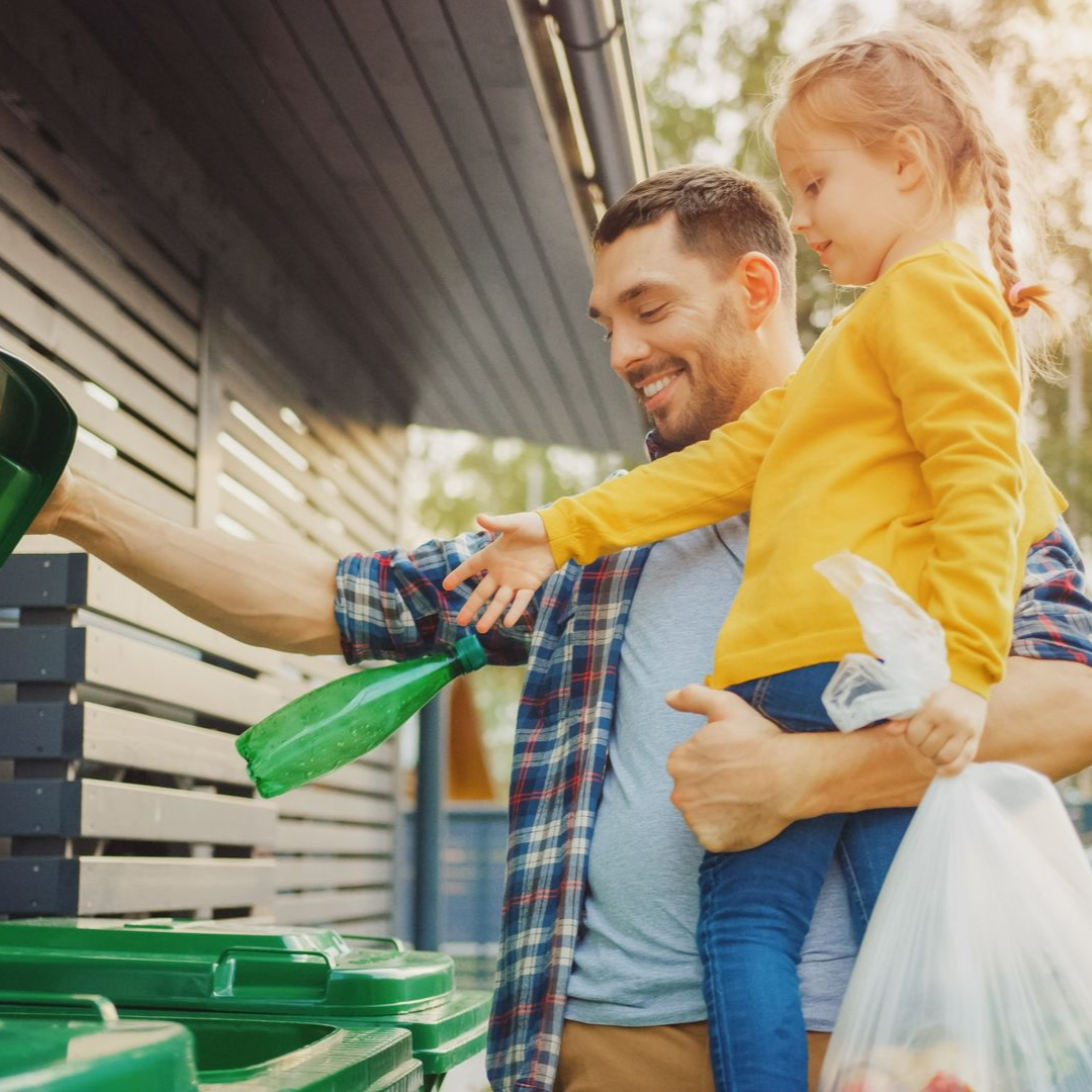 A green trash can with a piece of paper in it.