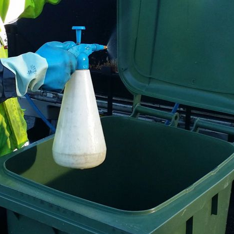 A green trash can with a piece of paper in it.