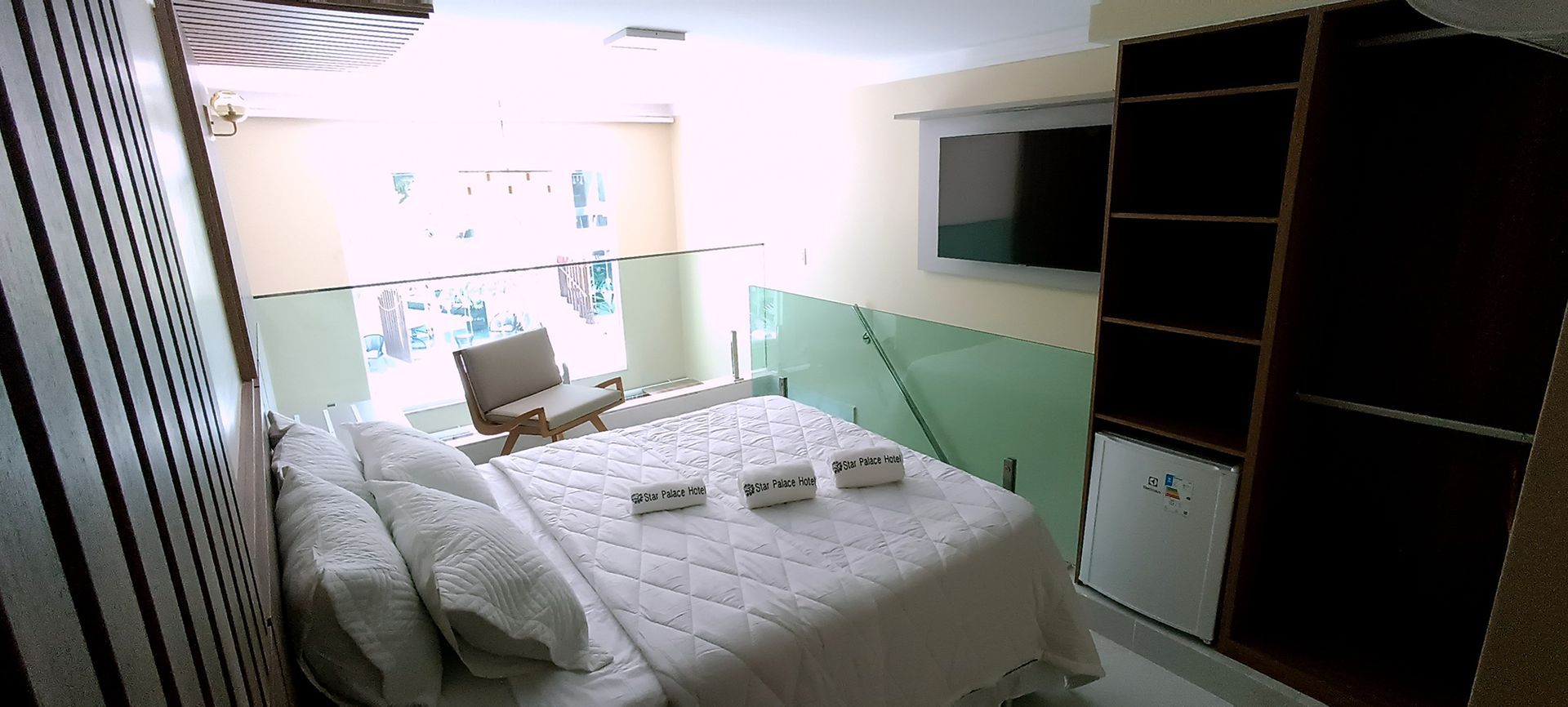 Um quarto de hotel com cama king size e TV de tela plana.