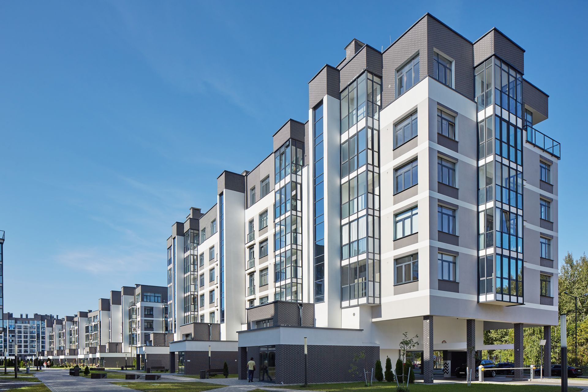 A large apartment building with a lot of windows and a lot of cars parked in front of it.