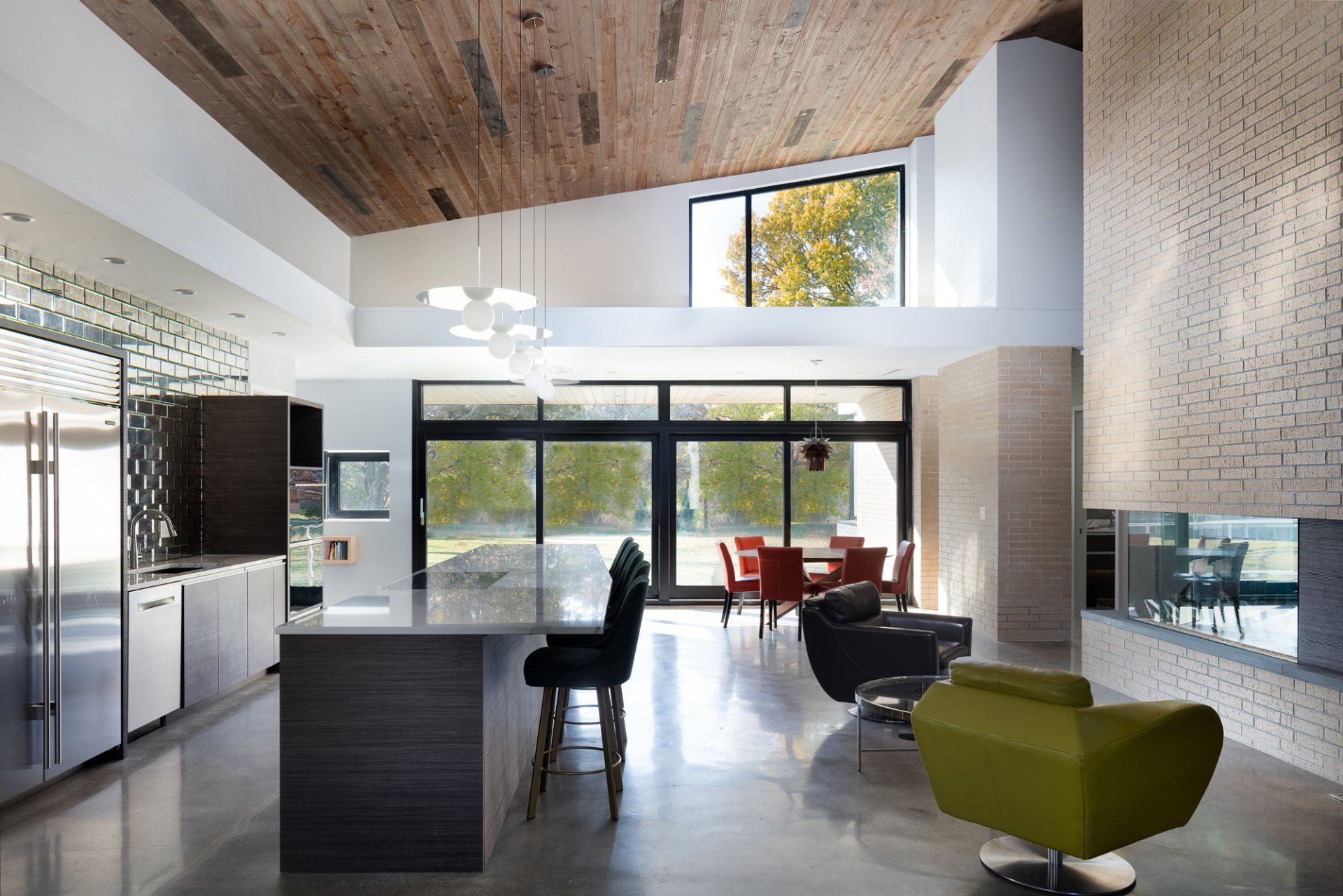 A modern style kitchen with large windows, high ceilings, and a large island in the center.