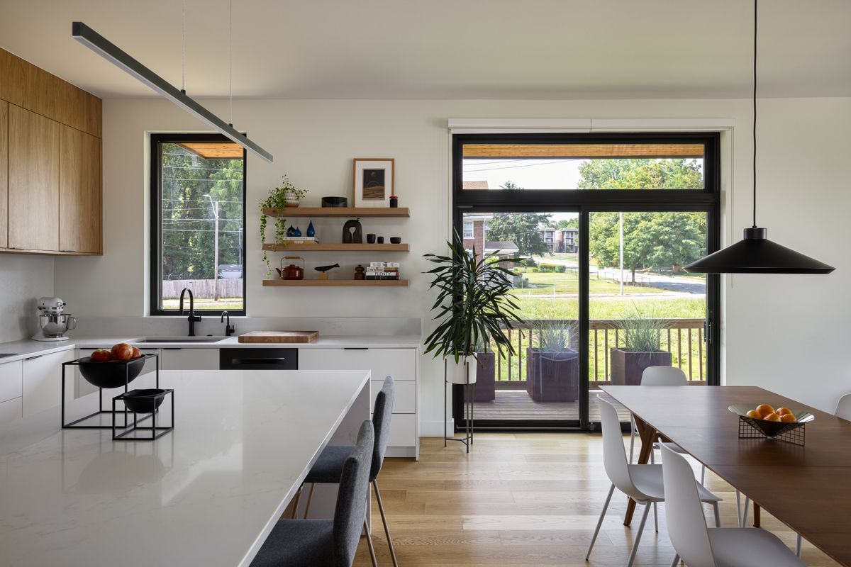 Modern style kitchen with island and kitchen table, looking out sliding doors open to a grassy field