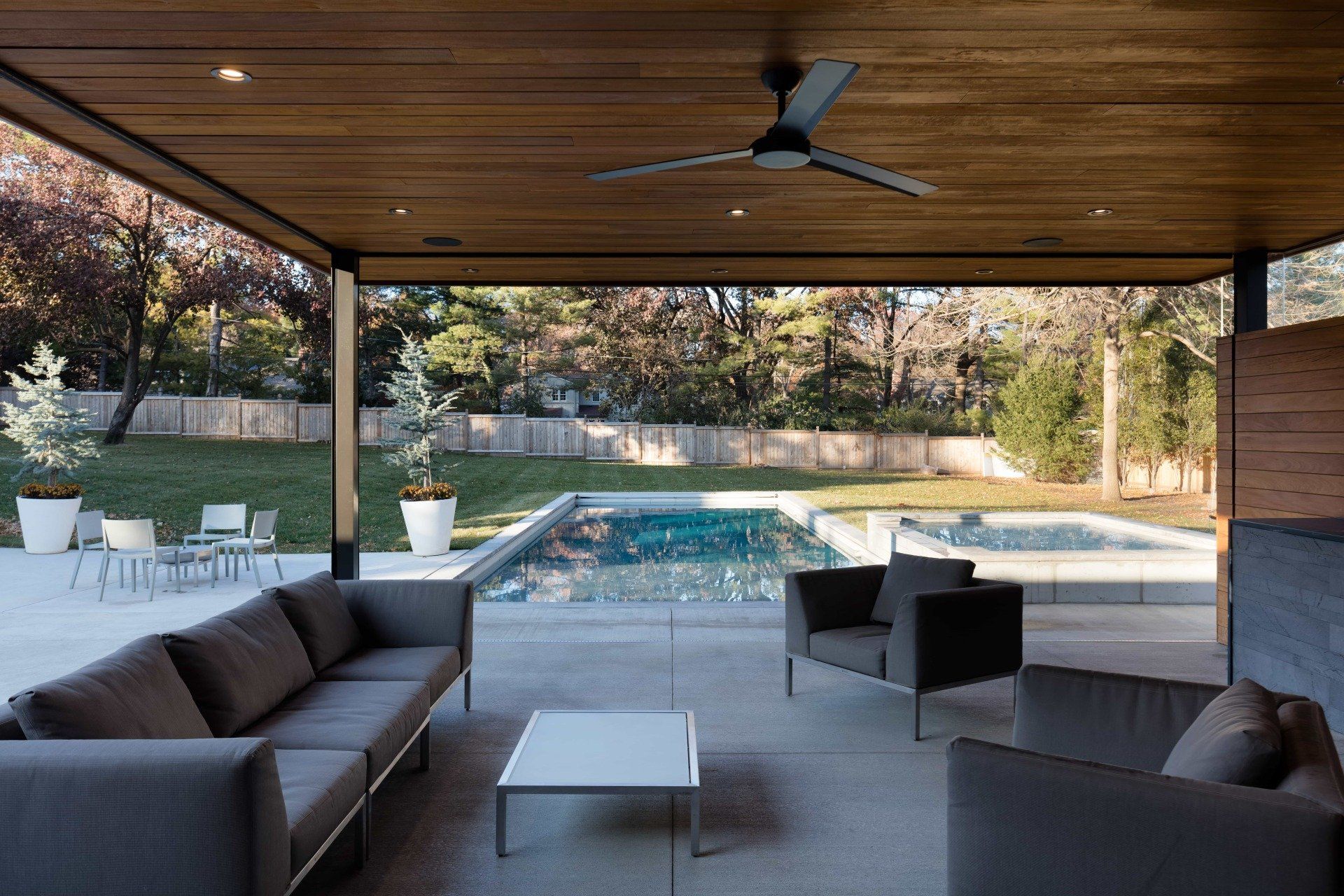 Backyard outdoor living area with sitting area next to pool and hot tub