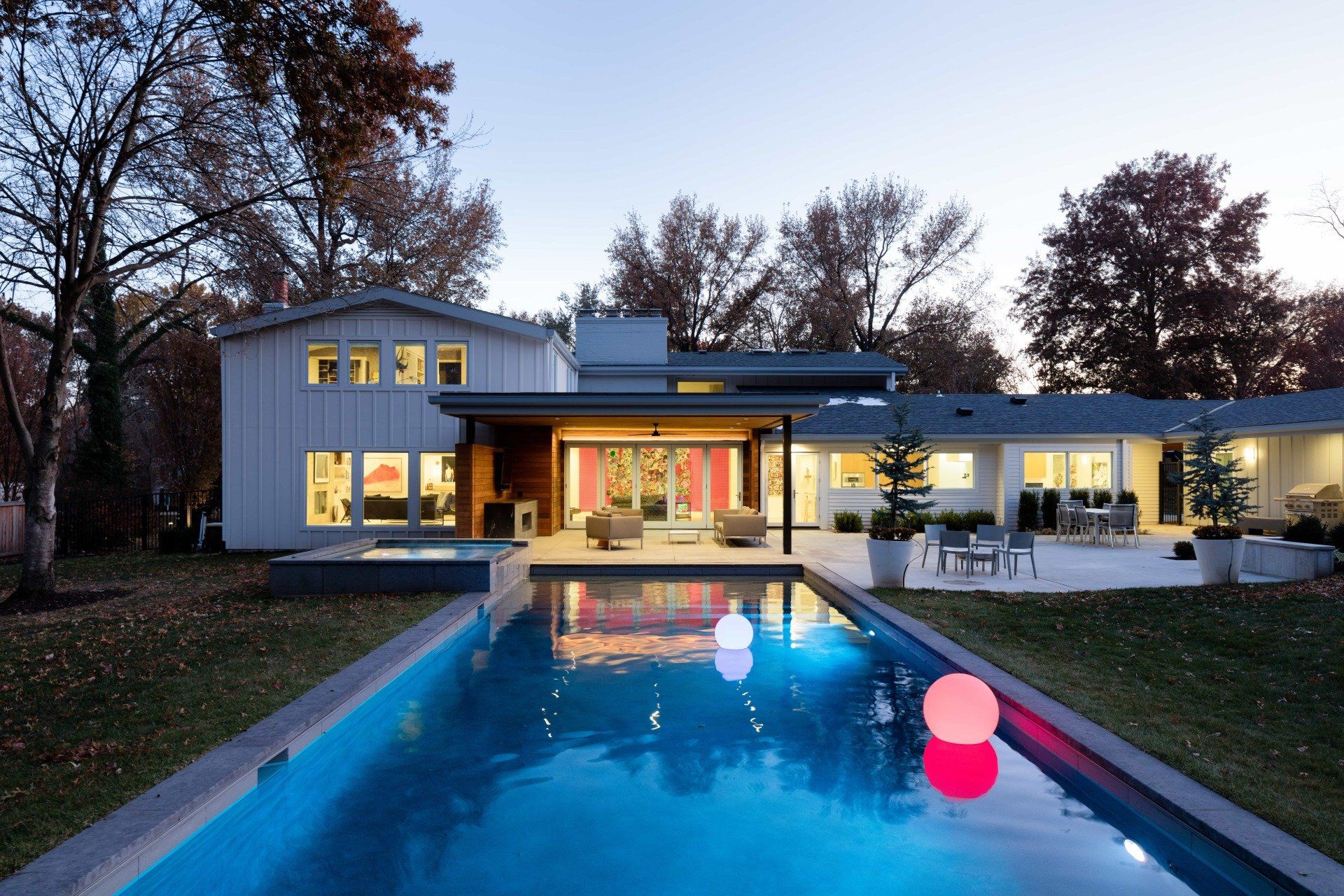Backyard with pool and outdoor living area lit up at night