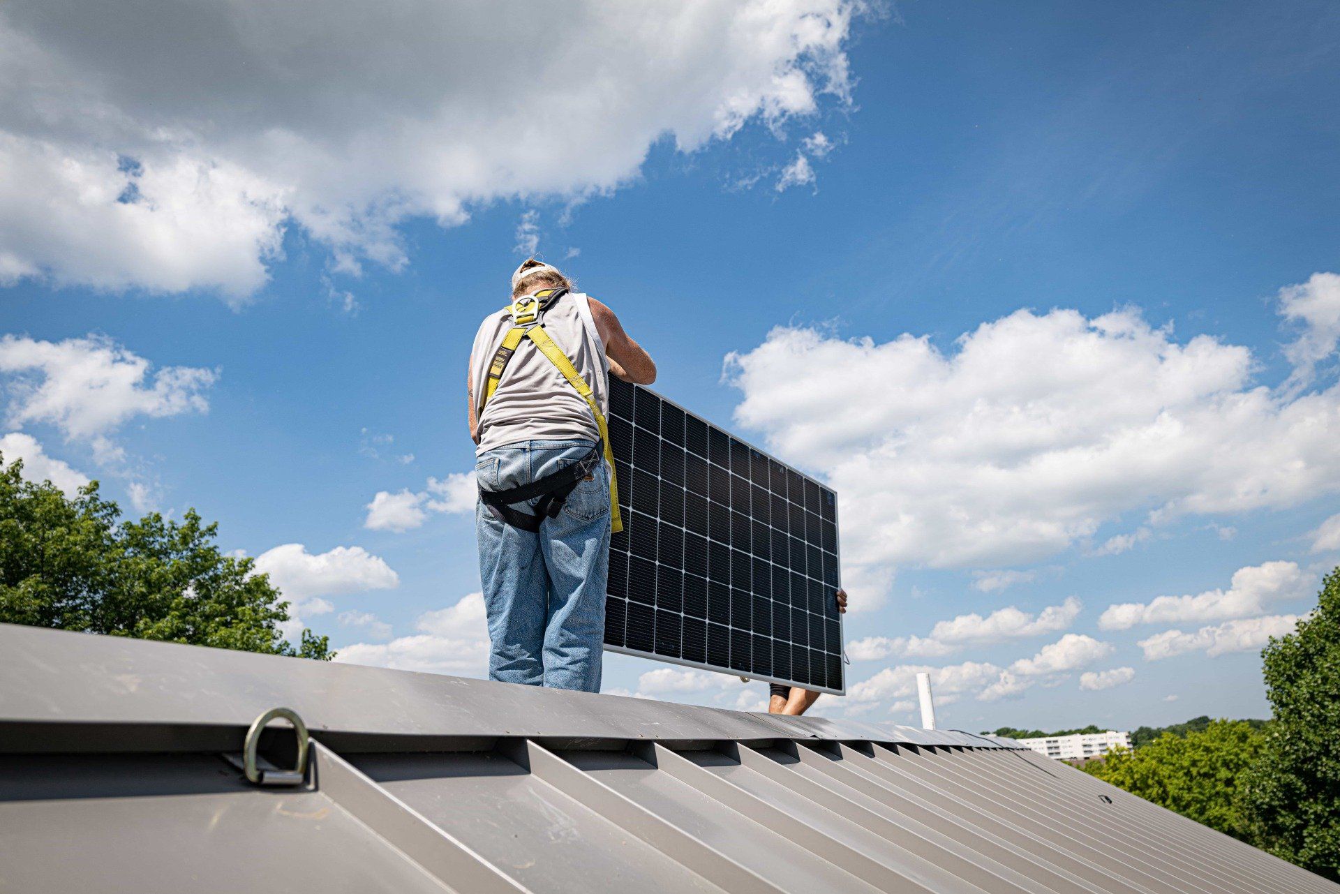 Man holding solar panel on metal roof