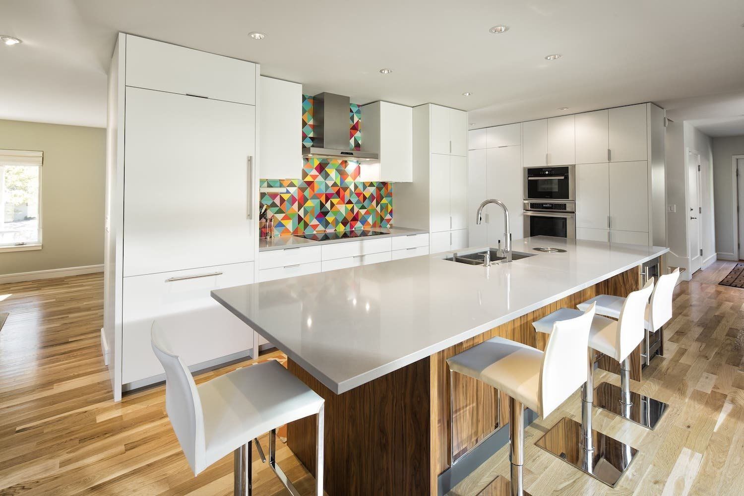 Modern kitchen with large island and colorful backsplash.