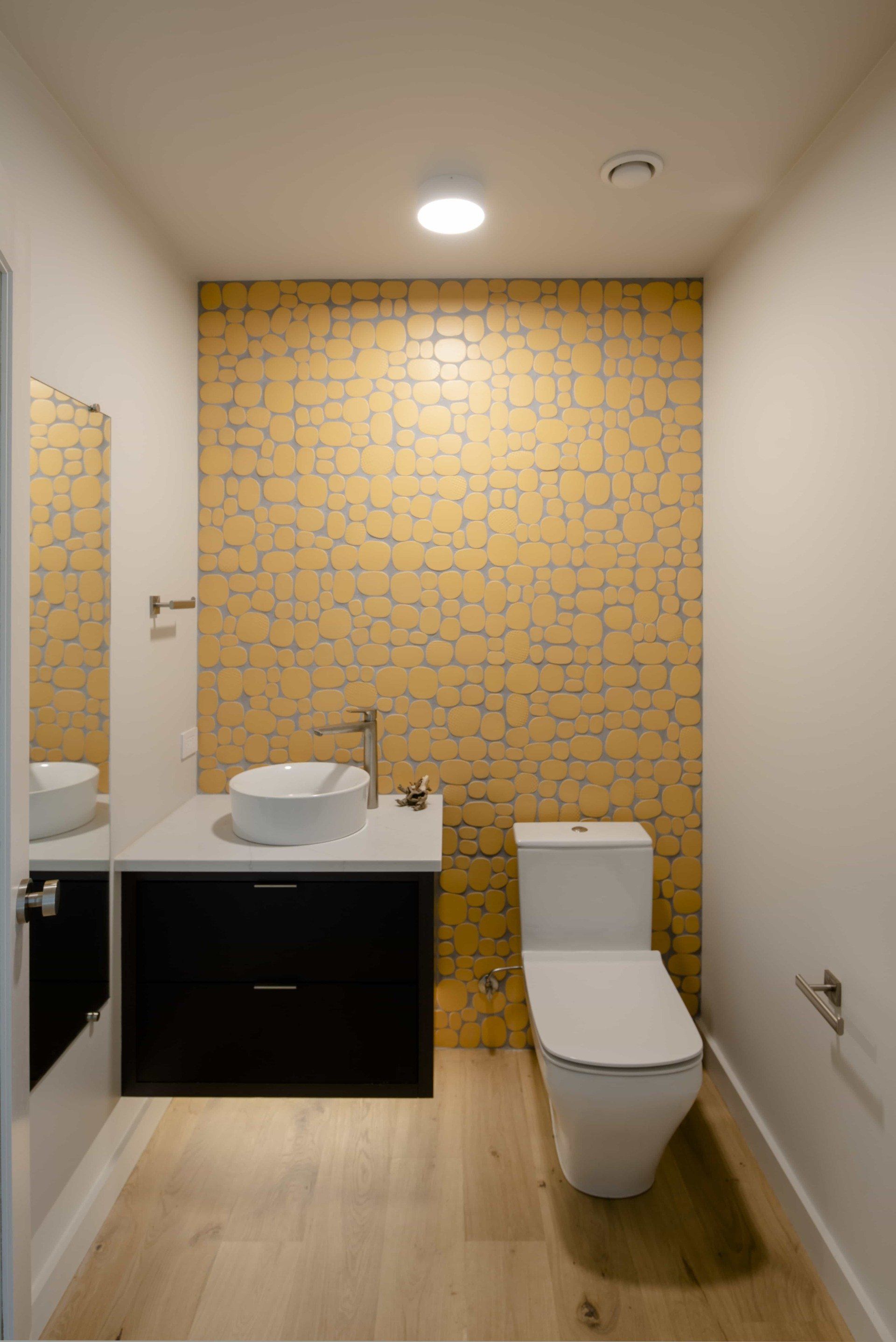 Small and cozy powder room with fun yellow backsplash and modern sink