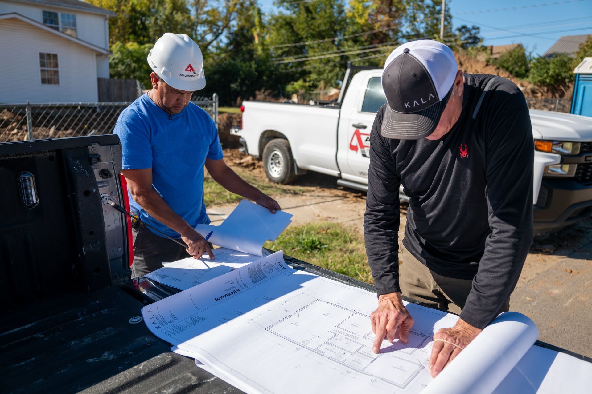 Two men at a construction site reviewing building plans 