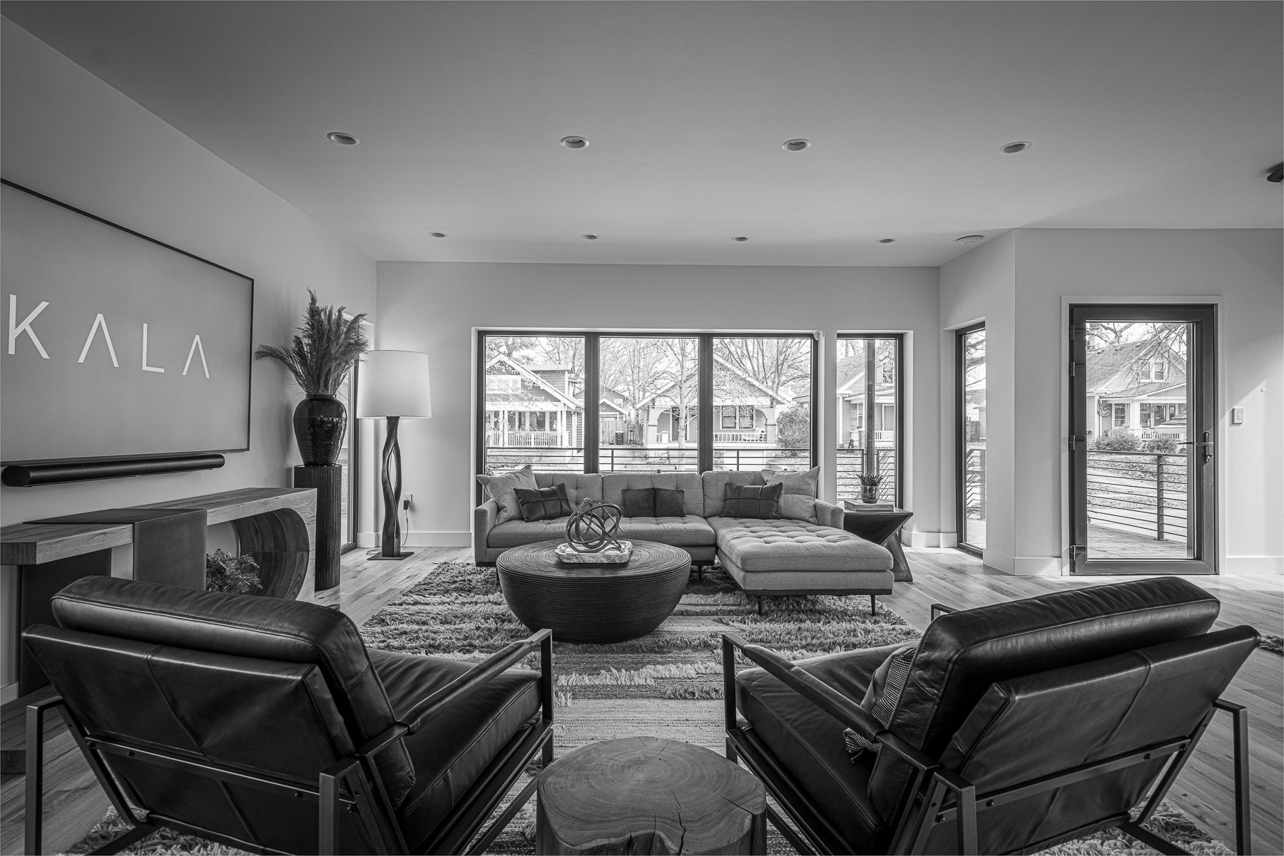 A black and white photo of a living room with a couch and chairs.