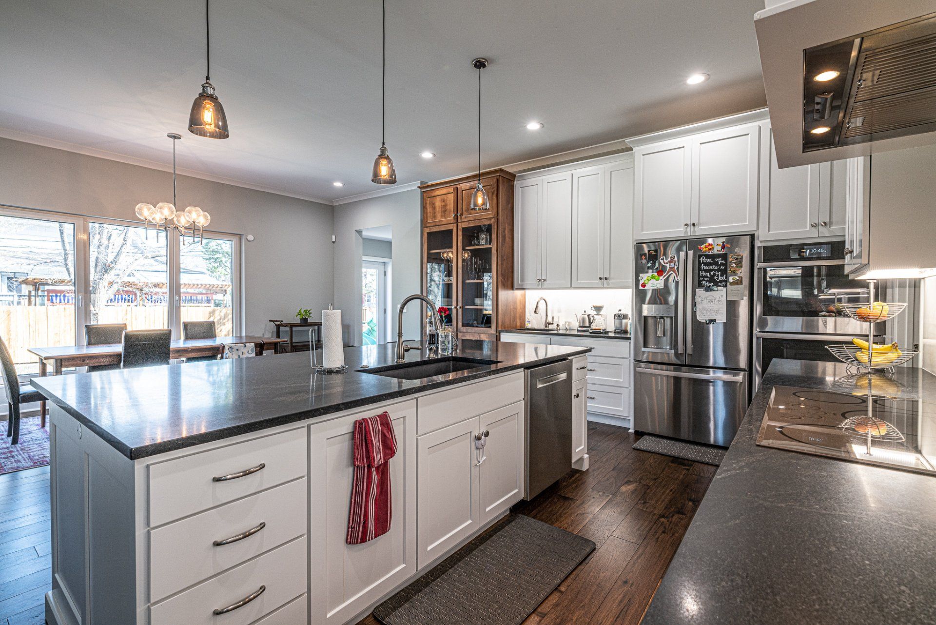 A modern kitchen with a large island and view out large windows.
