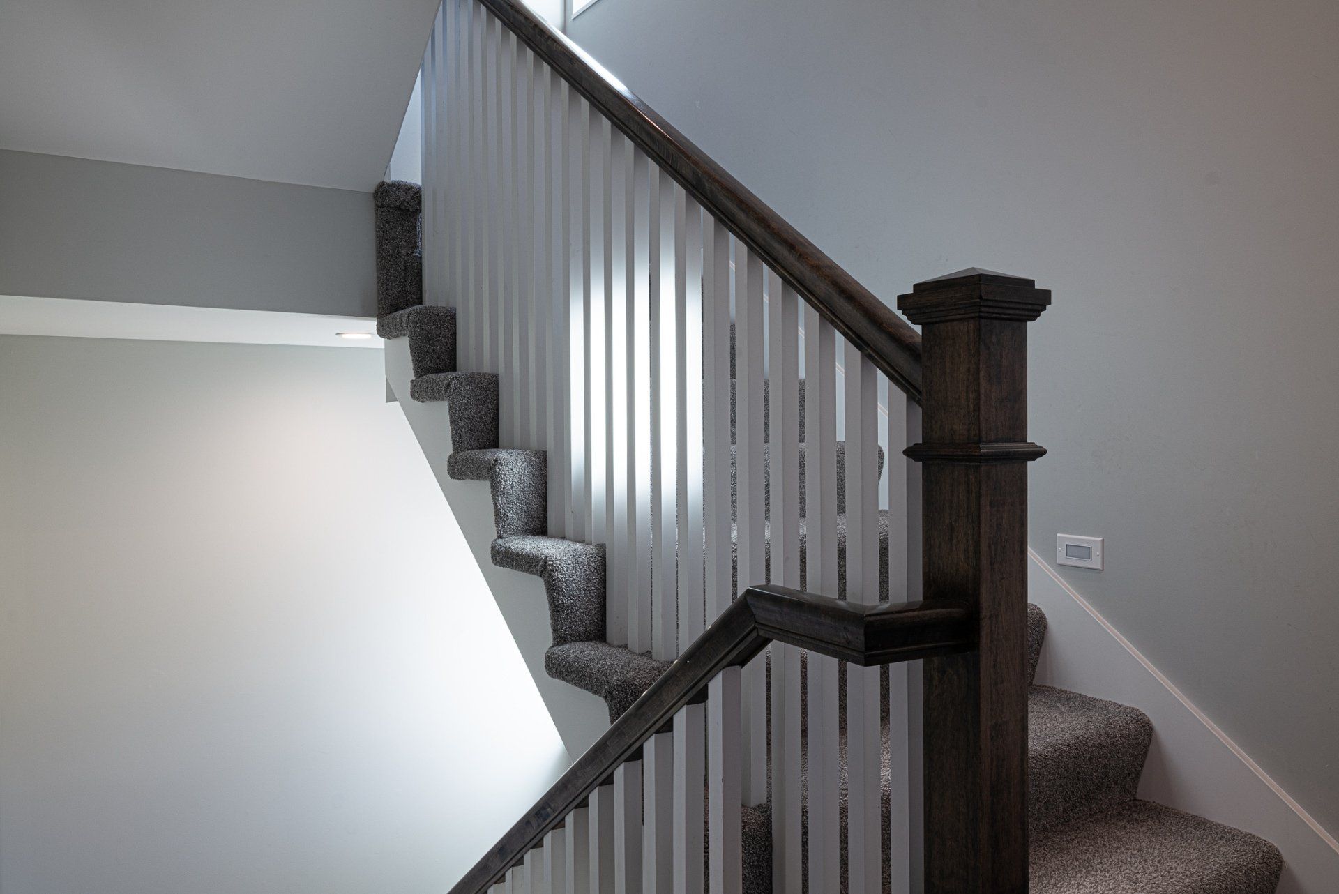 Stairwell with white beams and natural wood railing.