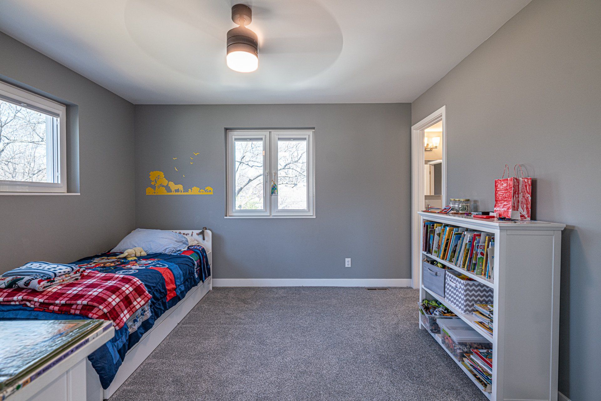 Child's bedroom with toddler bed, grey walls, and grey carpet.