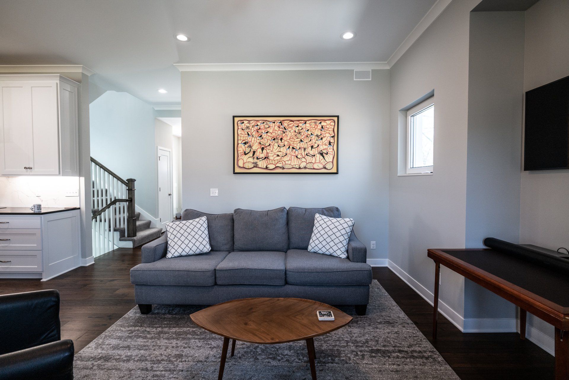 Living room with grey couch and modern painting on wall.