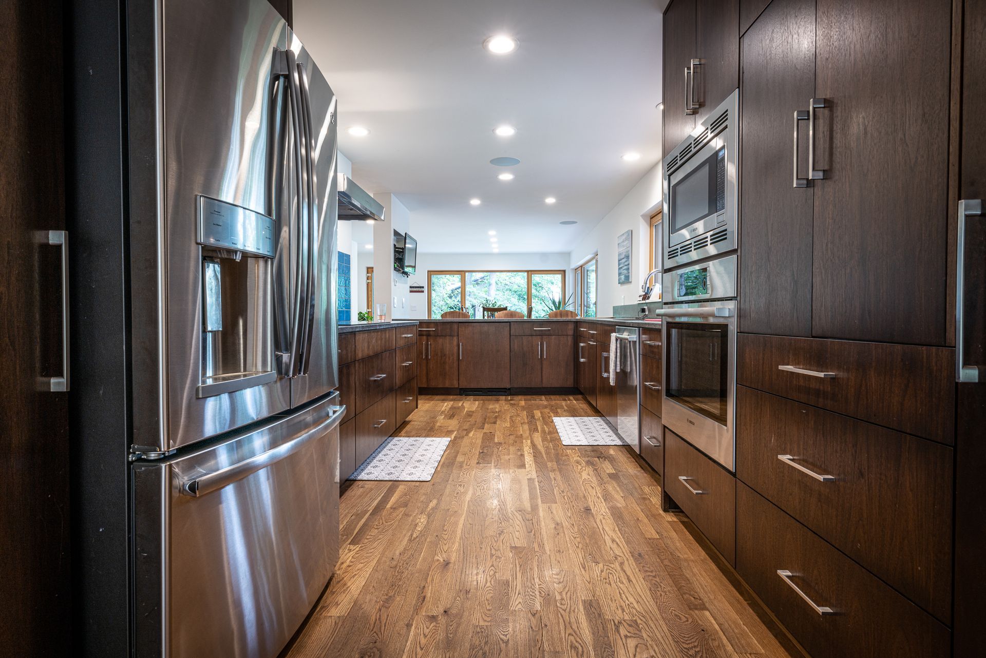 Stainless steel kitchen appliances, wood floor, and a view of a dining room