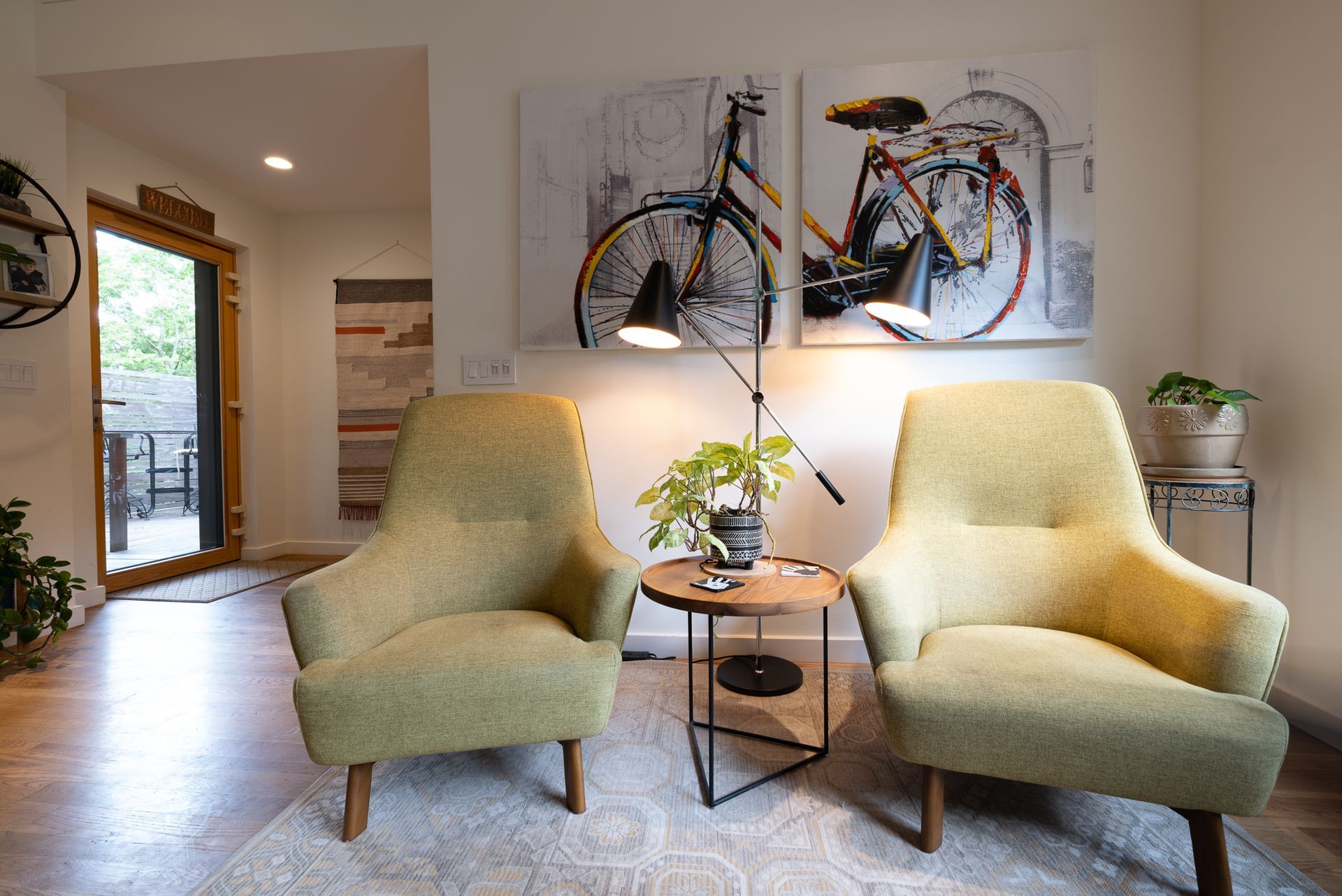 Two yellow-green chairs with lamp between them and large, modern painting