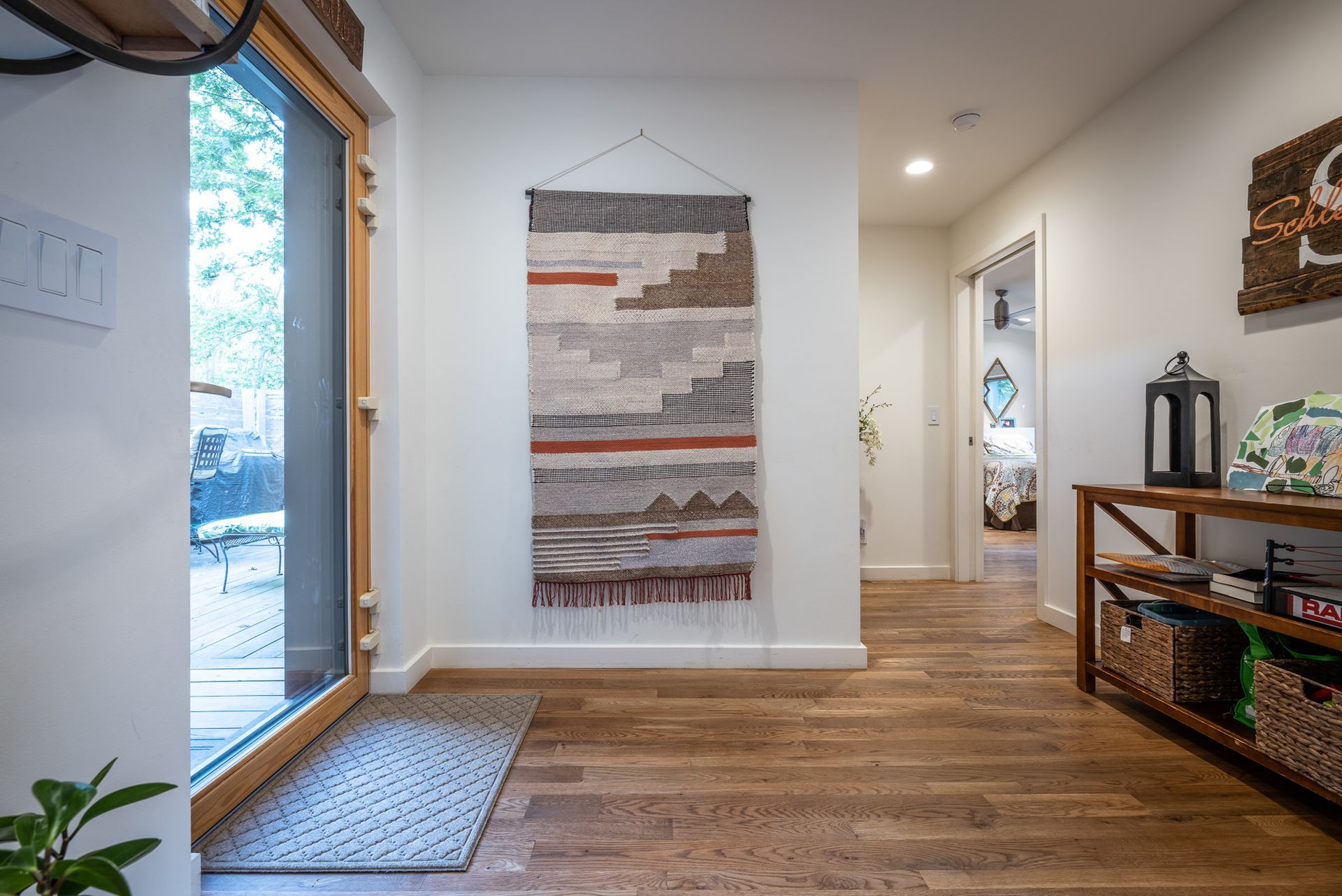 Entryway to house with large glass door and hanging woven art