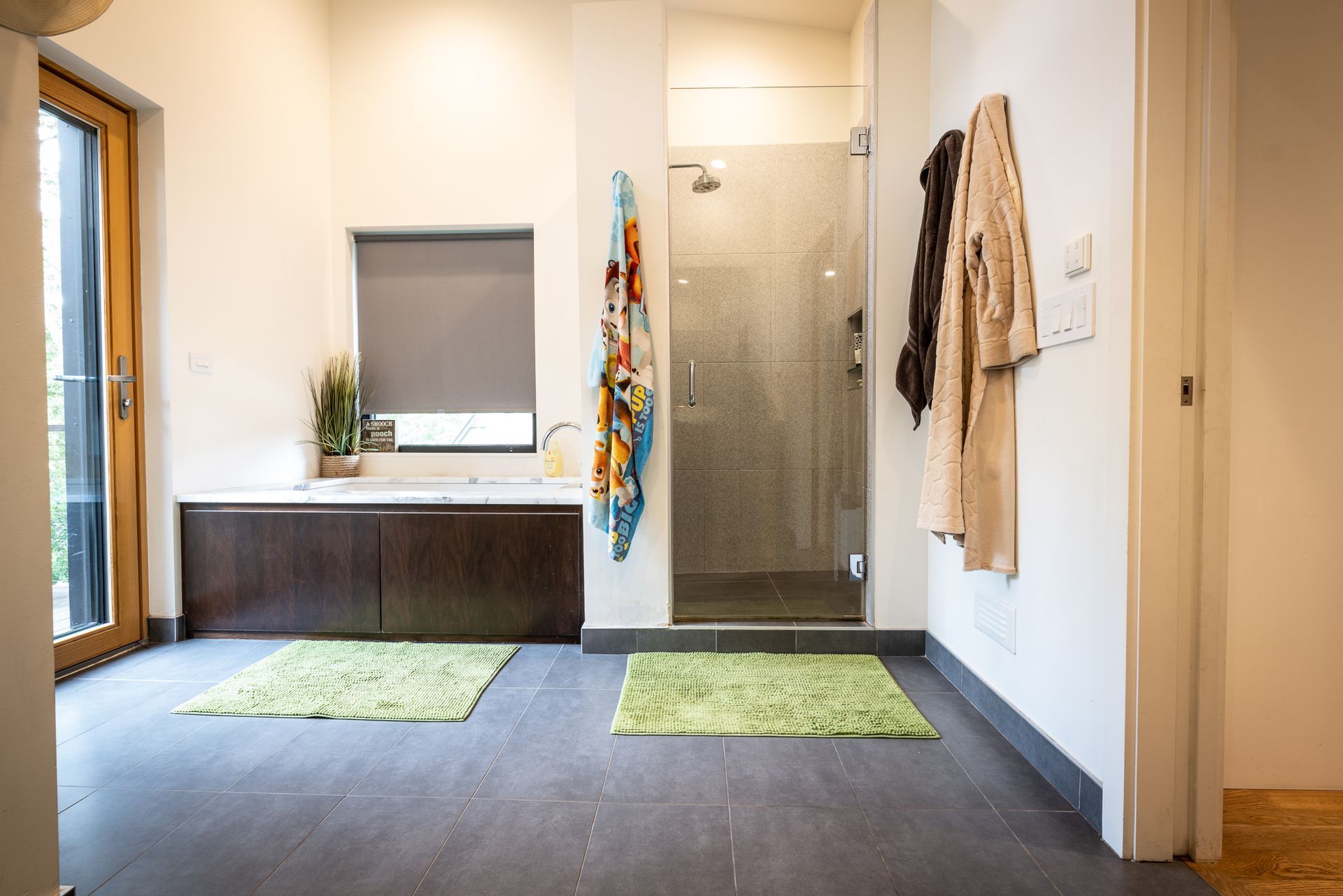 Primary bathroom with abundant natural light and green accent rugs