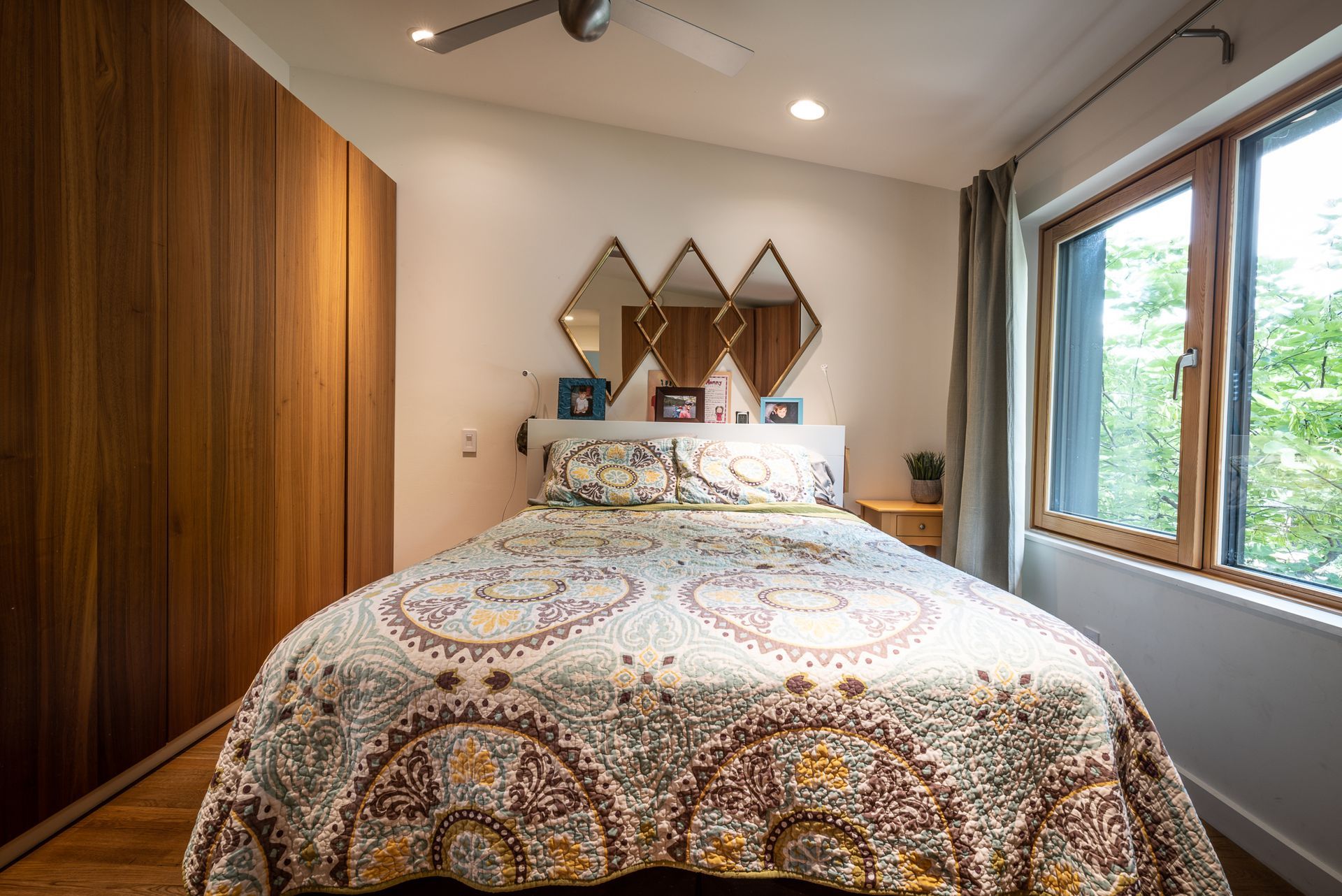 Primary bedroom with queen sized bed, large windows, and wooden custom cabinetry.